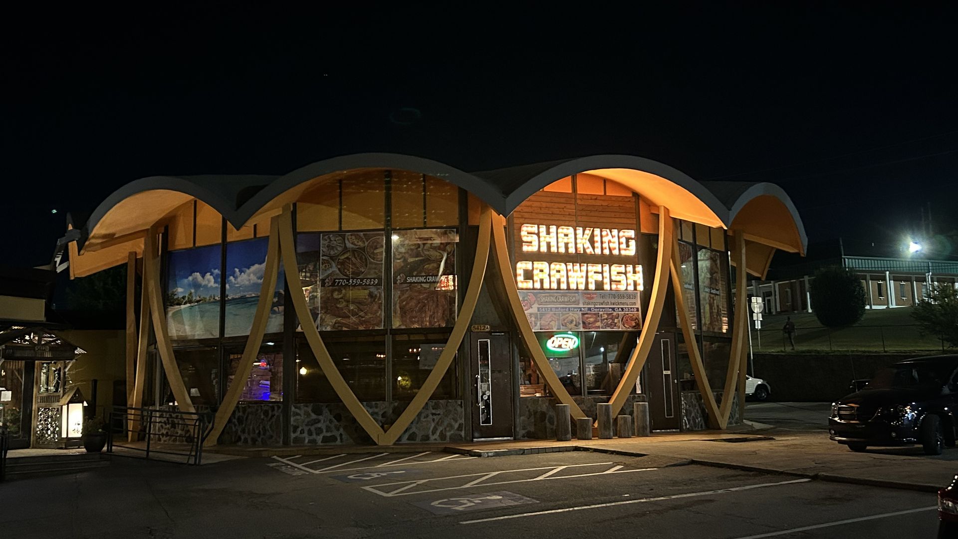 A building with a sign that says shaking crawfish at night time