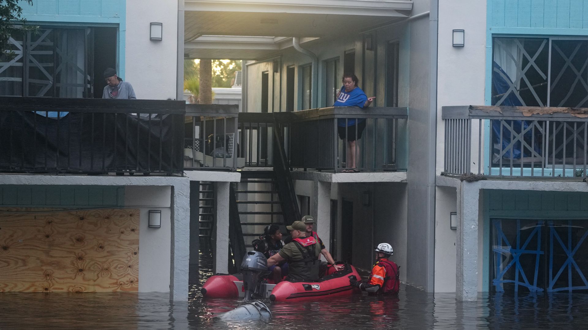 Rescue officials in a boat rescue a young man from an apartment complex in waist-high water.