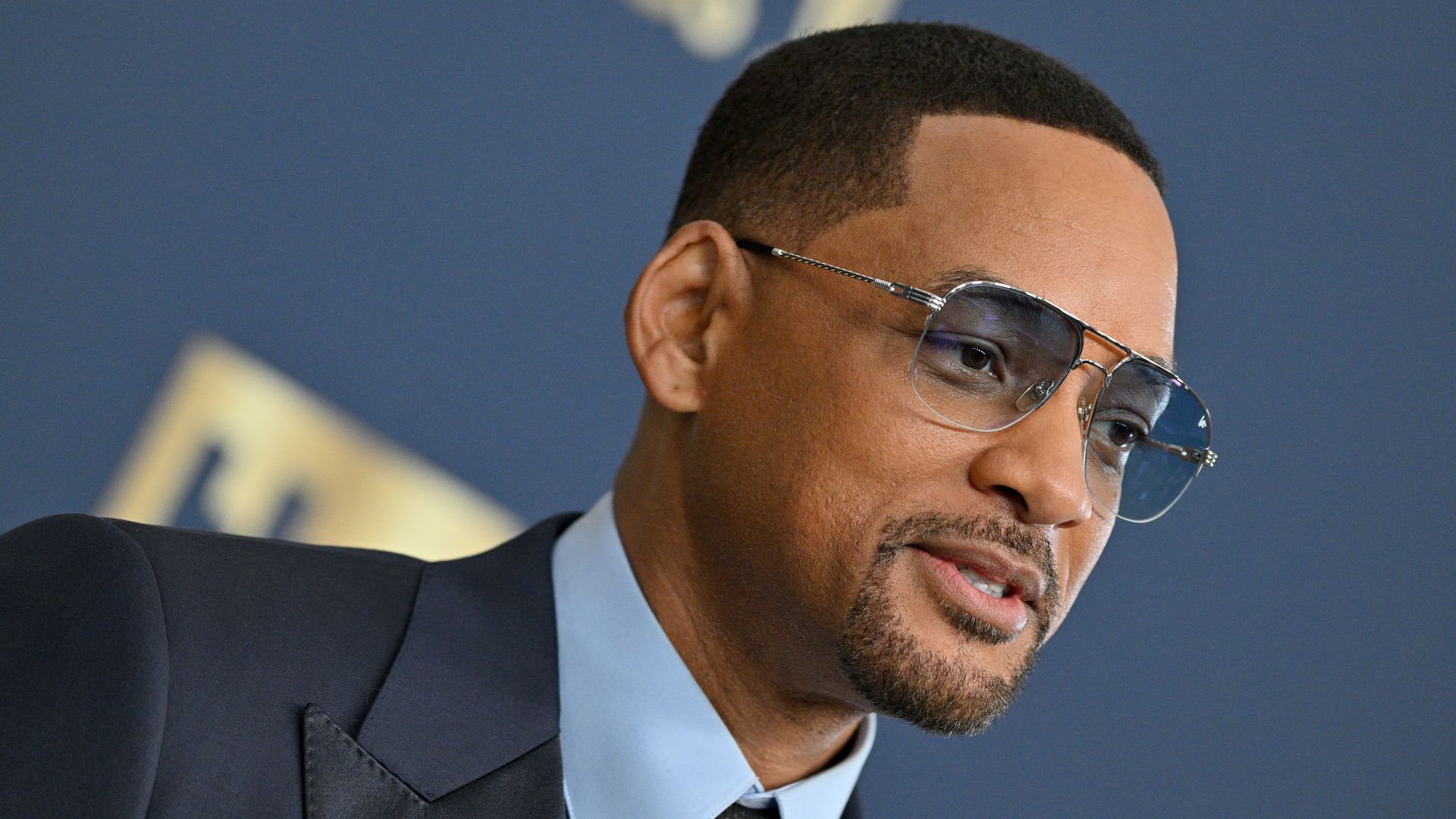 Photo of Will Smith wearing aviators and a suit