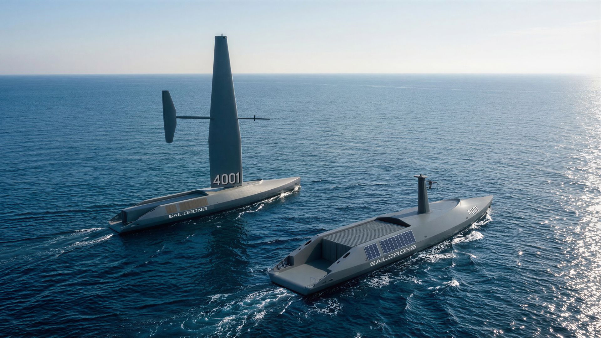 Two futuristic Saildrone vessels ride the calm blue sea under a clear sky.