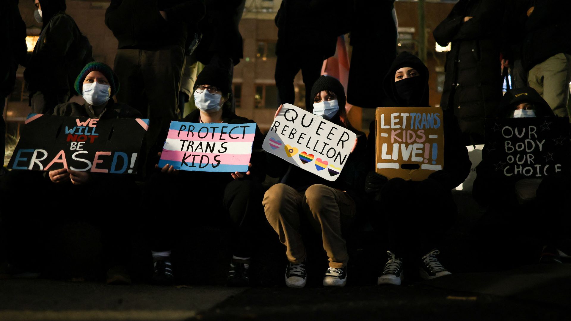 Four protestors sit with signs 