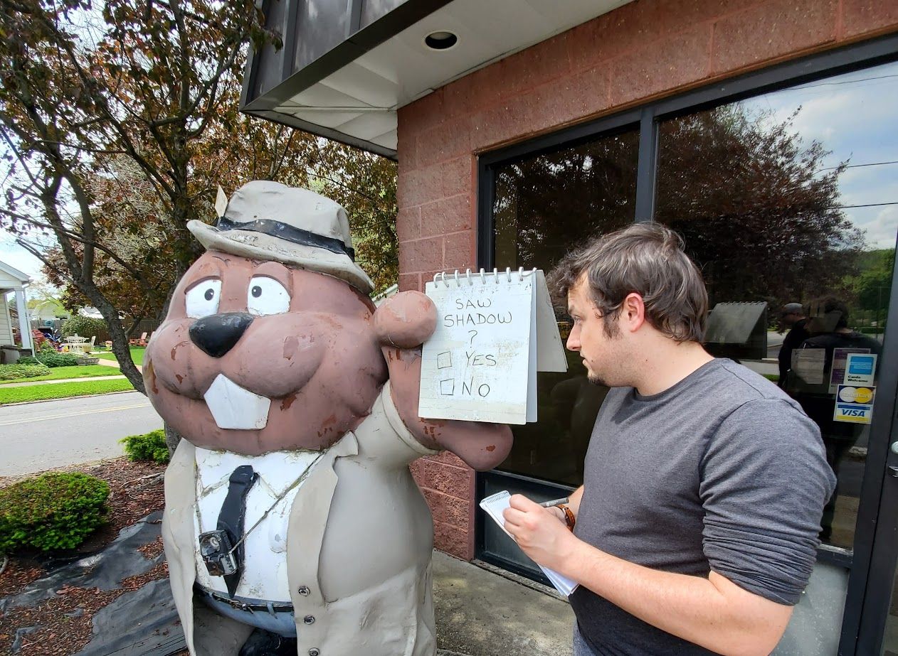 A statue of a Punxsutawney groundhog wearing a reporter's outfit, holding a notebook. 