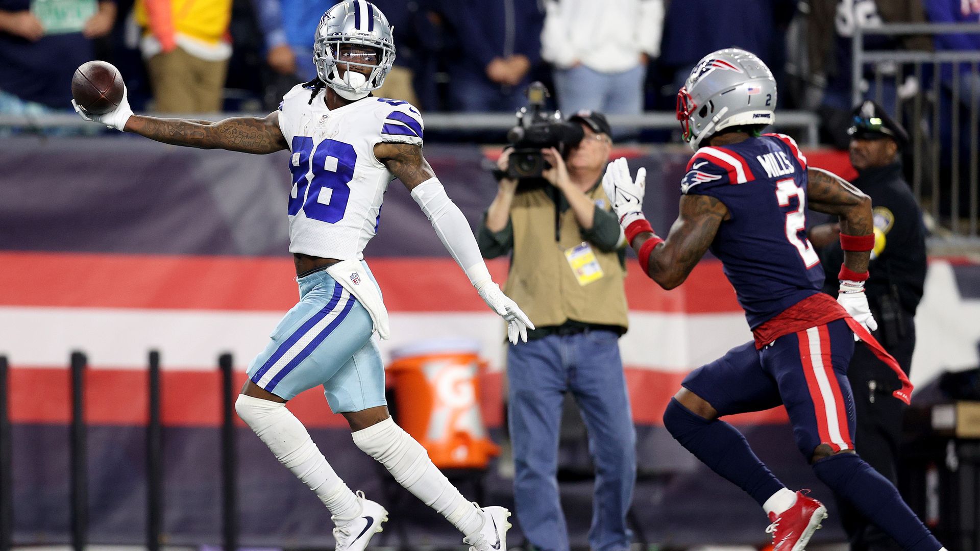 CeeDee Lamb extends the football with his right hand to taunt a New England player.