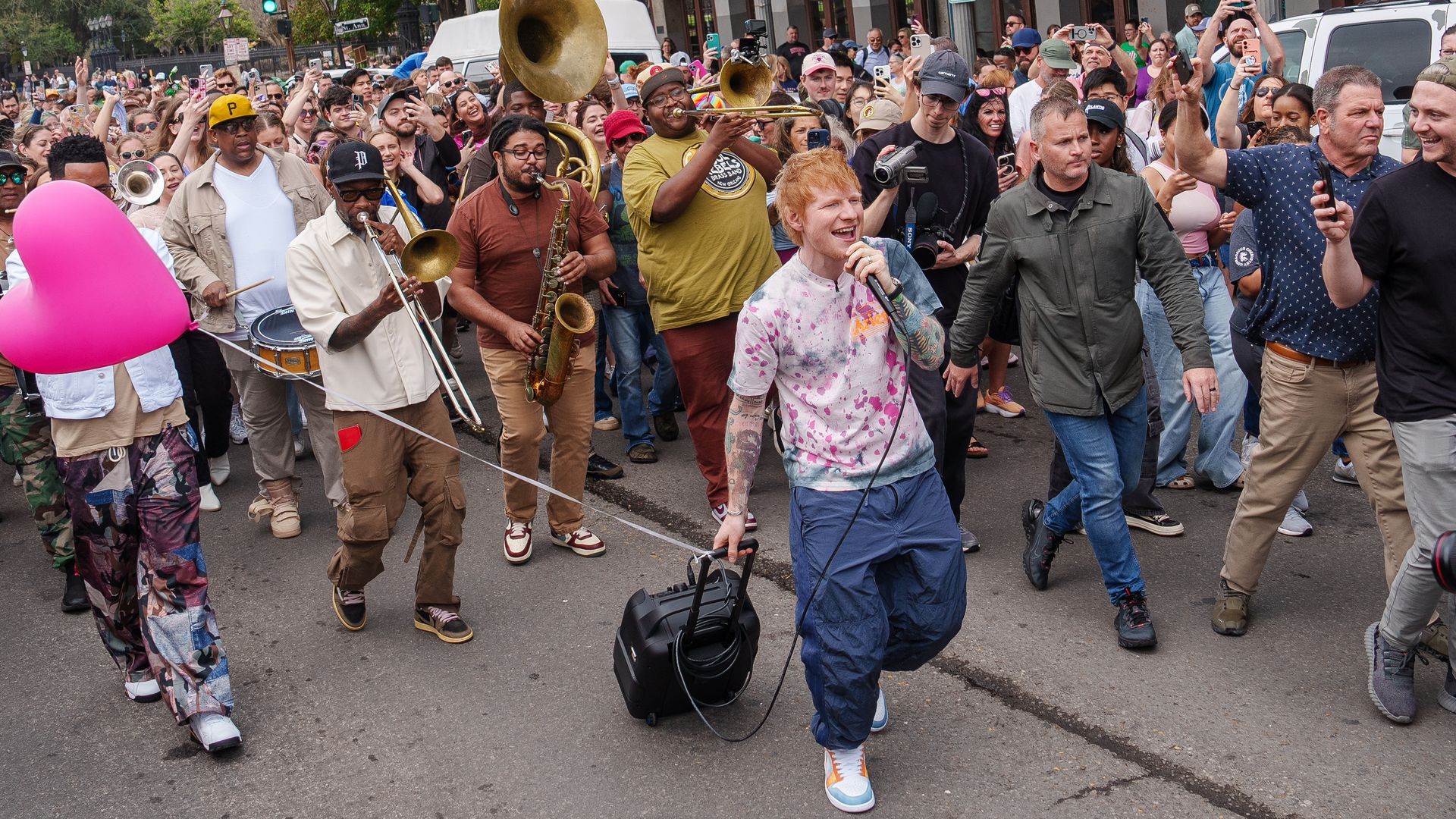 Photo shows Ed Sheeran singing with a crowd.