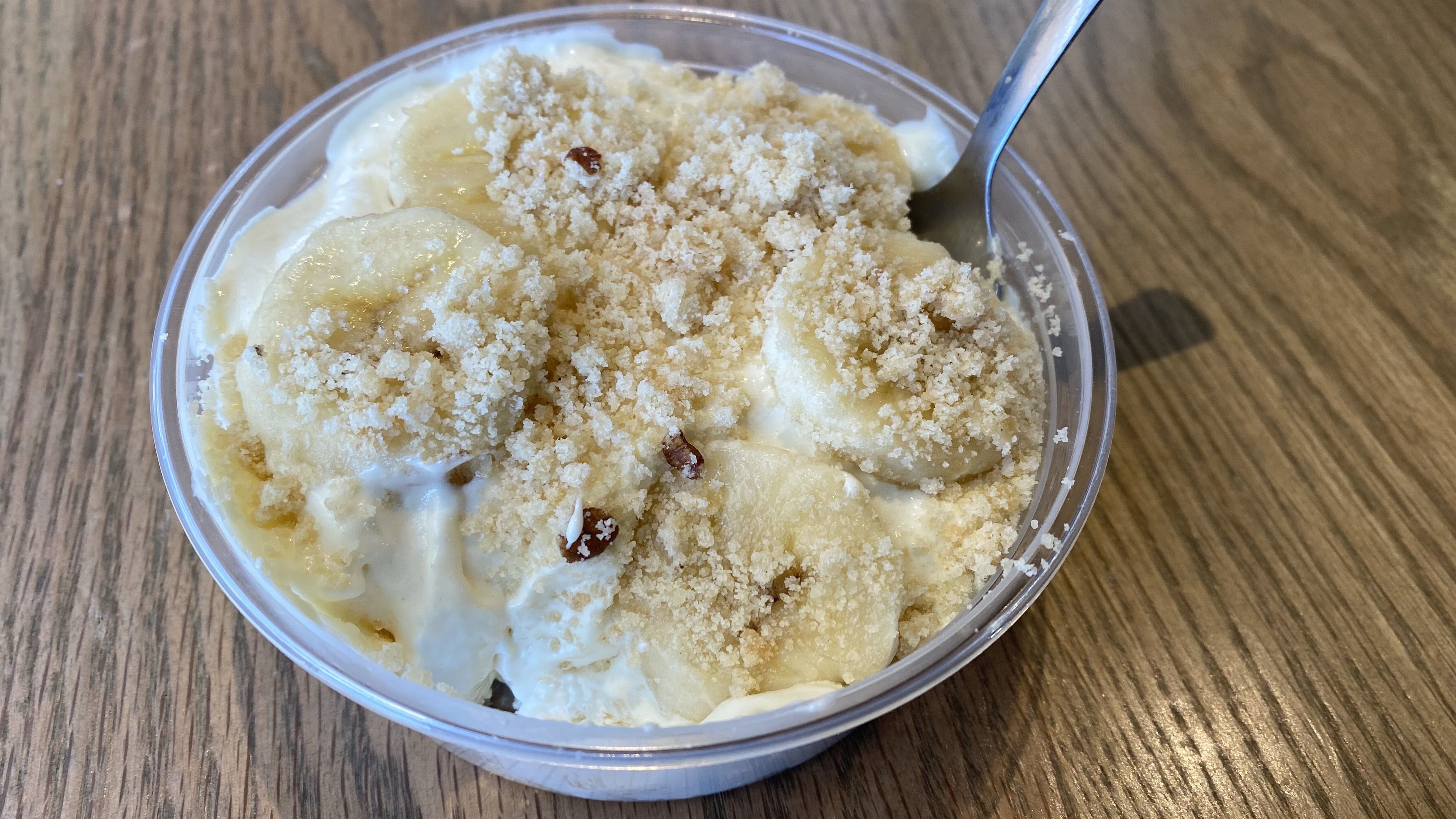 A photo of banana pudding in a plastic cup with a spoon dug in. 