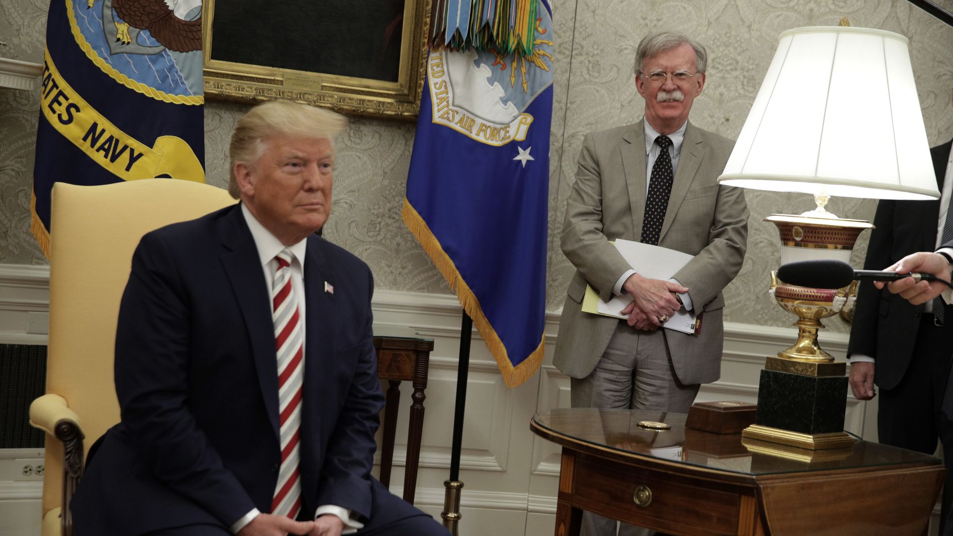 Photo of John Bolton standing behind Donald Trump as Trump is being interviewed