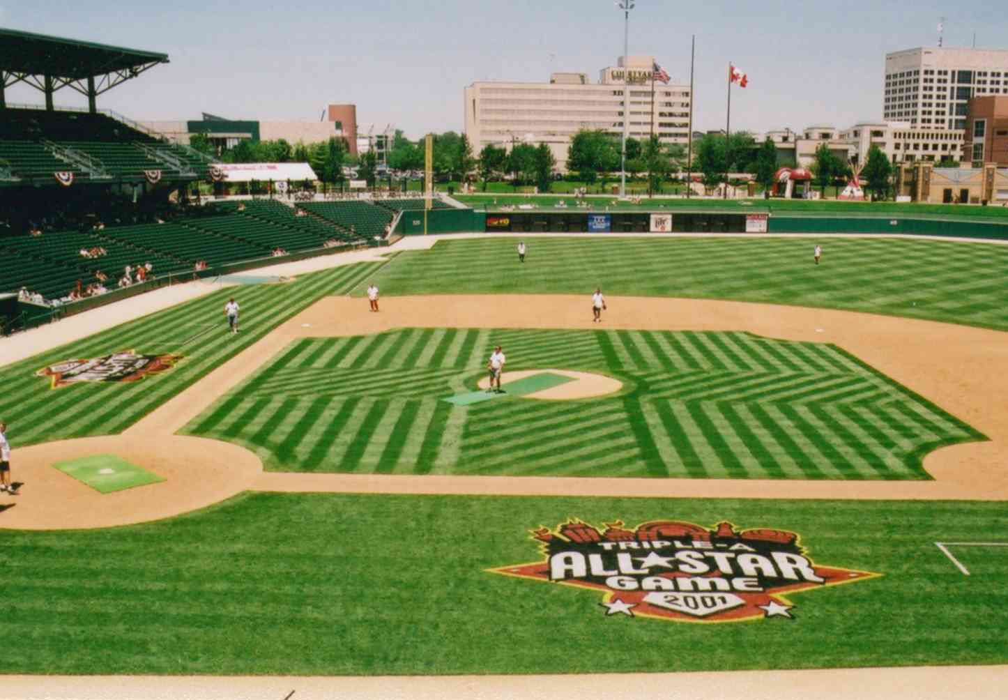 Wide view of a baseball stadium for an All-Star Game; striped infield grass, players on the field, stands to the left, and an All-Star Game 2001 logo on the outfield grass.