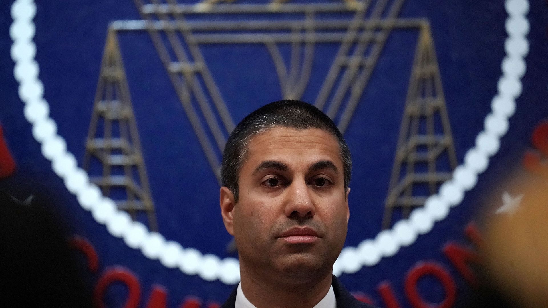 FCC Chairman Ajit Pai sits in front of the seal of the agency