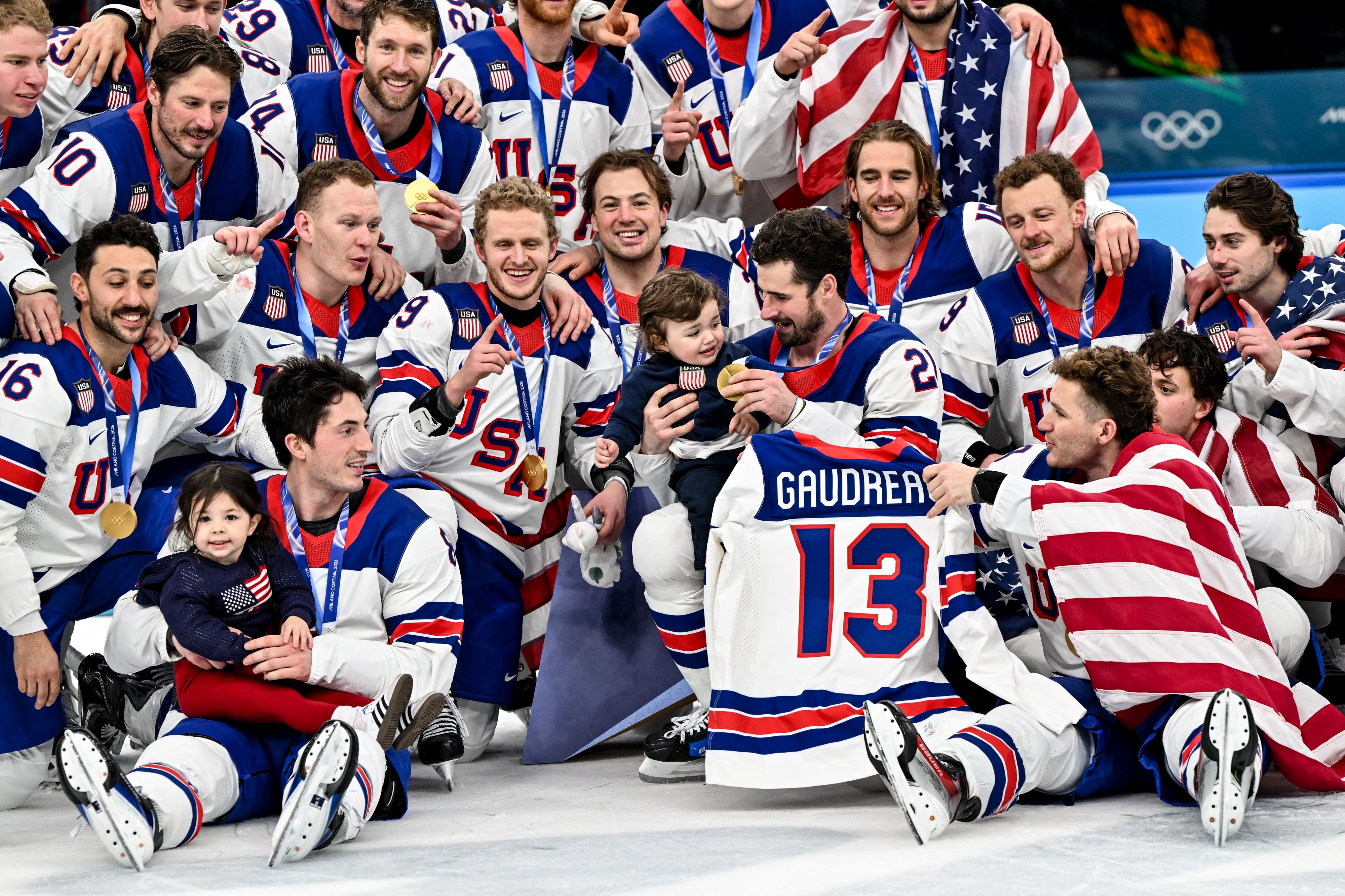 Team USA poses for a group photo with the two children and jersey of the late Johnny Gaudreau.