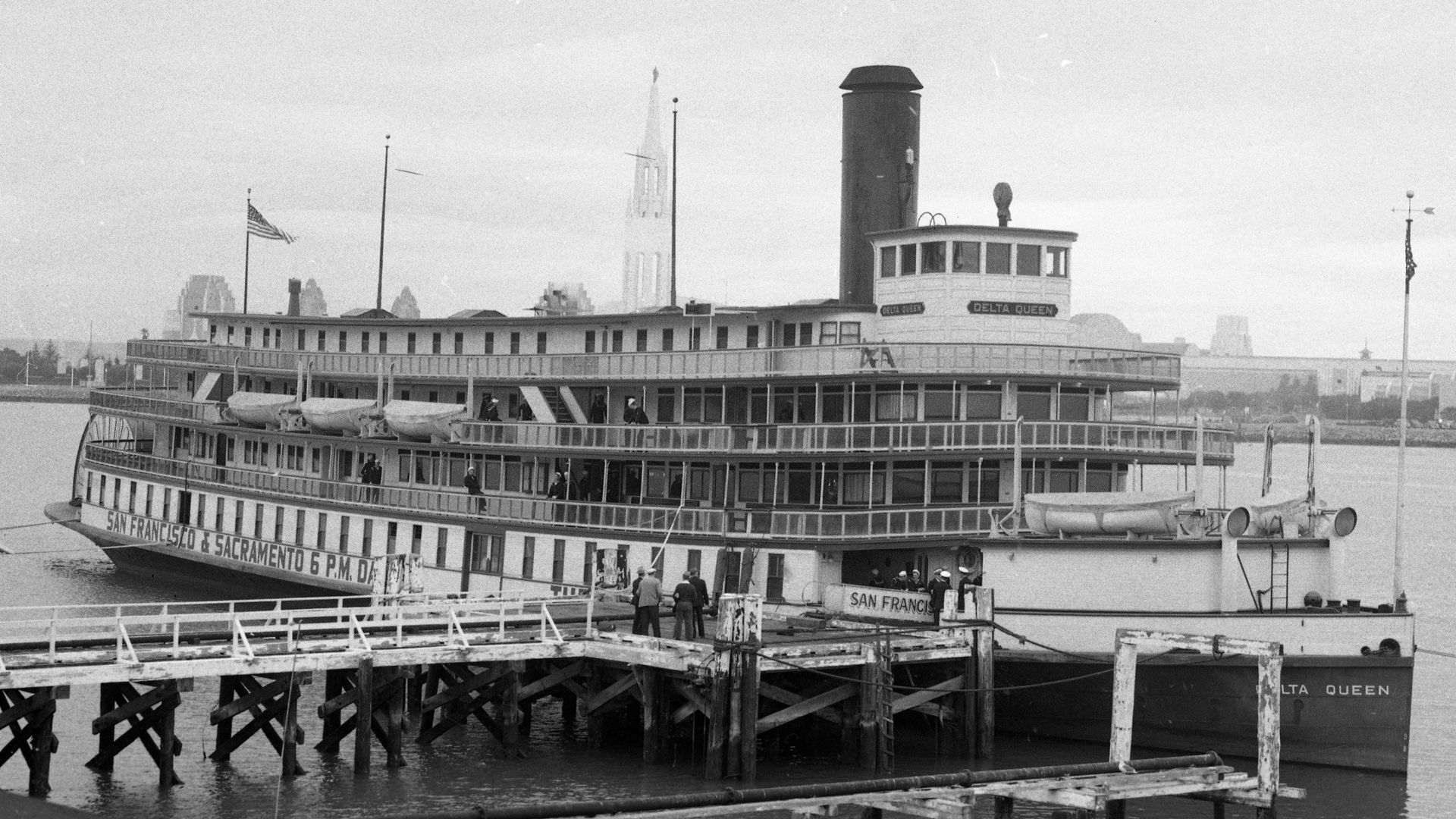 A vintage, black and white image of a steamboat docked at a port.