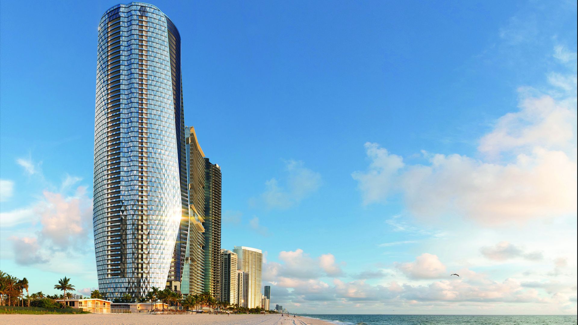 A silvery condominium stands tall beside the beach with a blue sky above. 