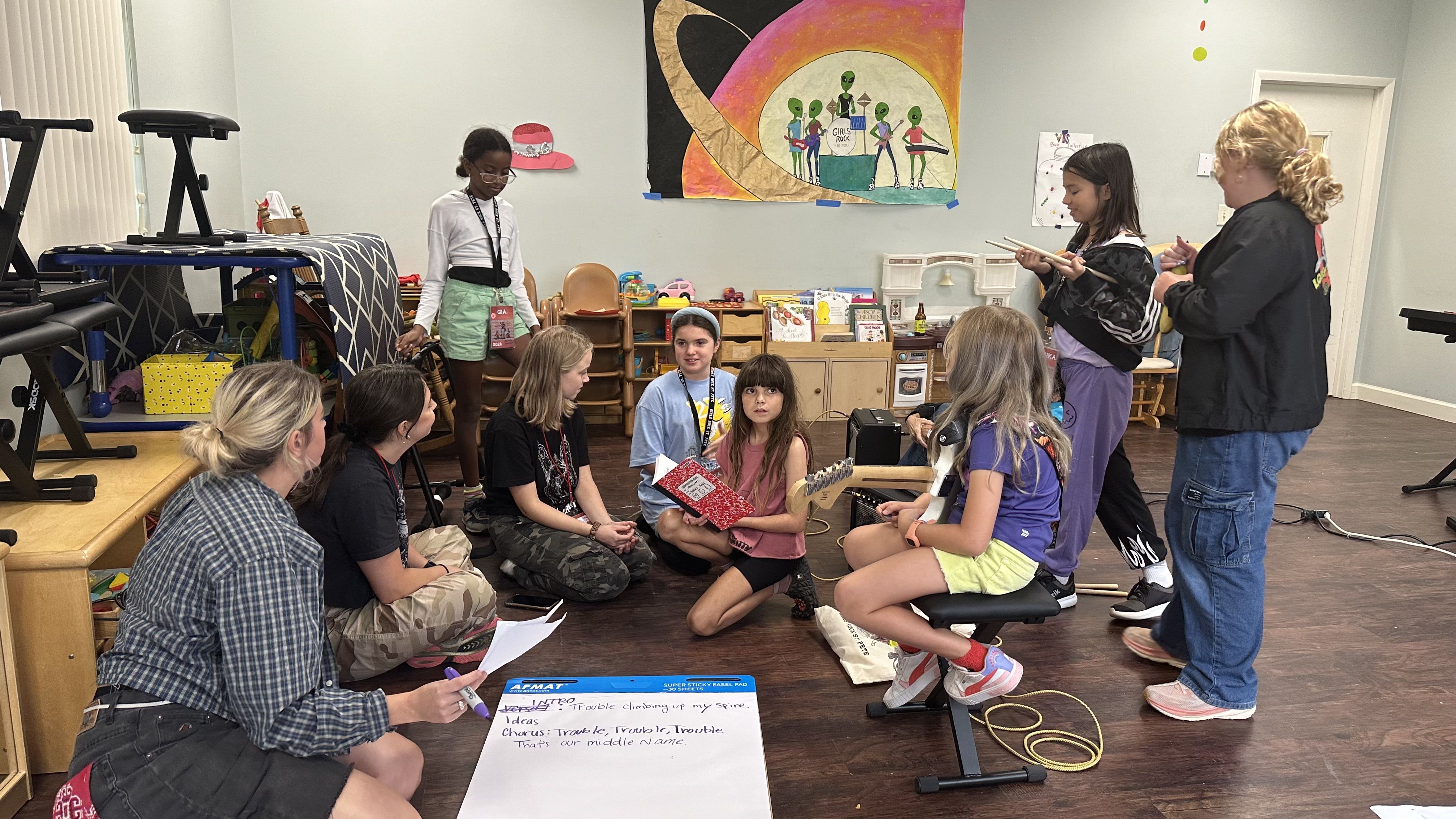A group of young girls sit around a sheet of paper with lyrics