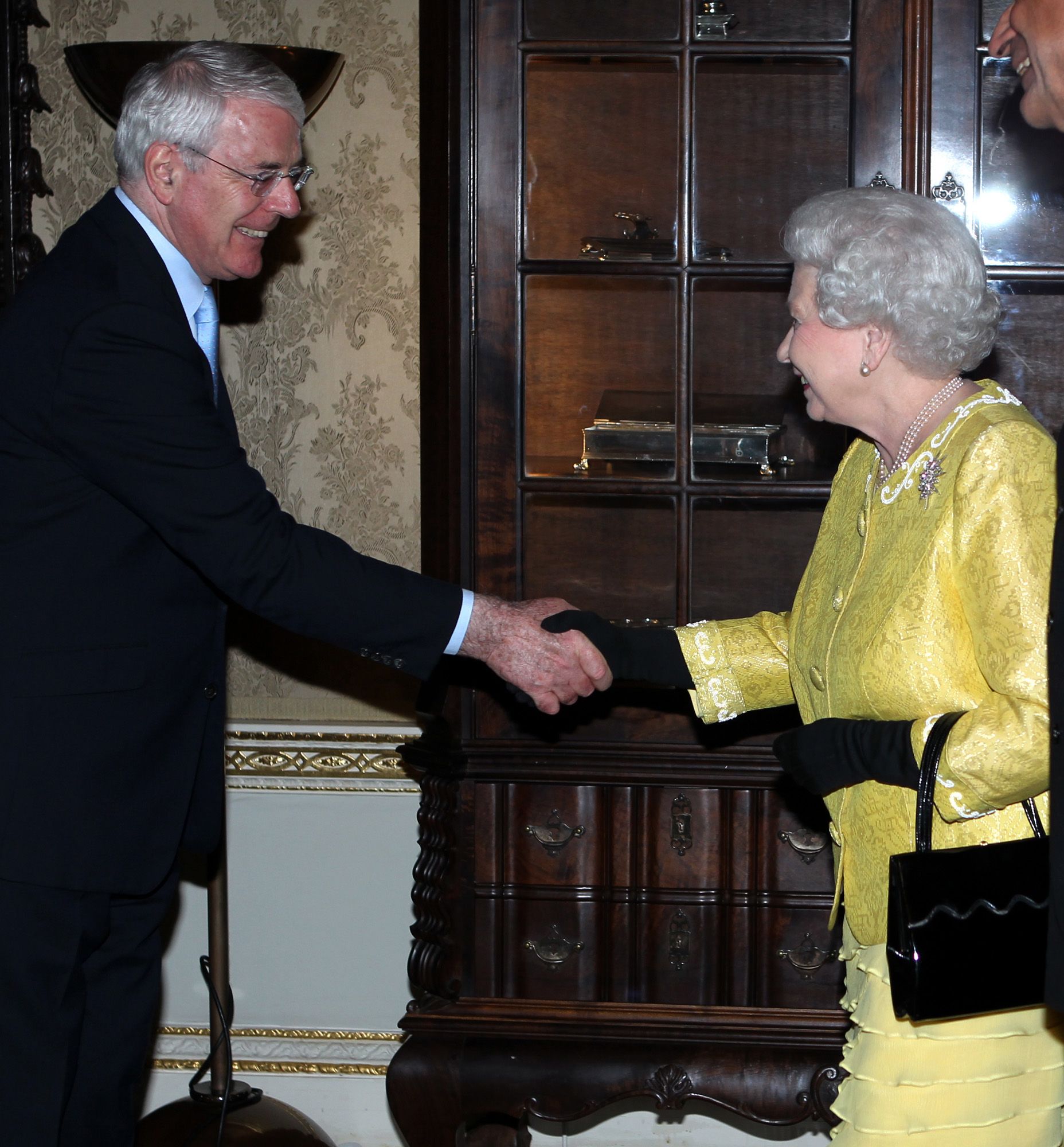 Former Prime Minister John Major shakes hands with Queen Elizabeth II in 2012.