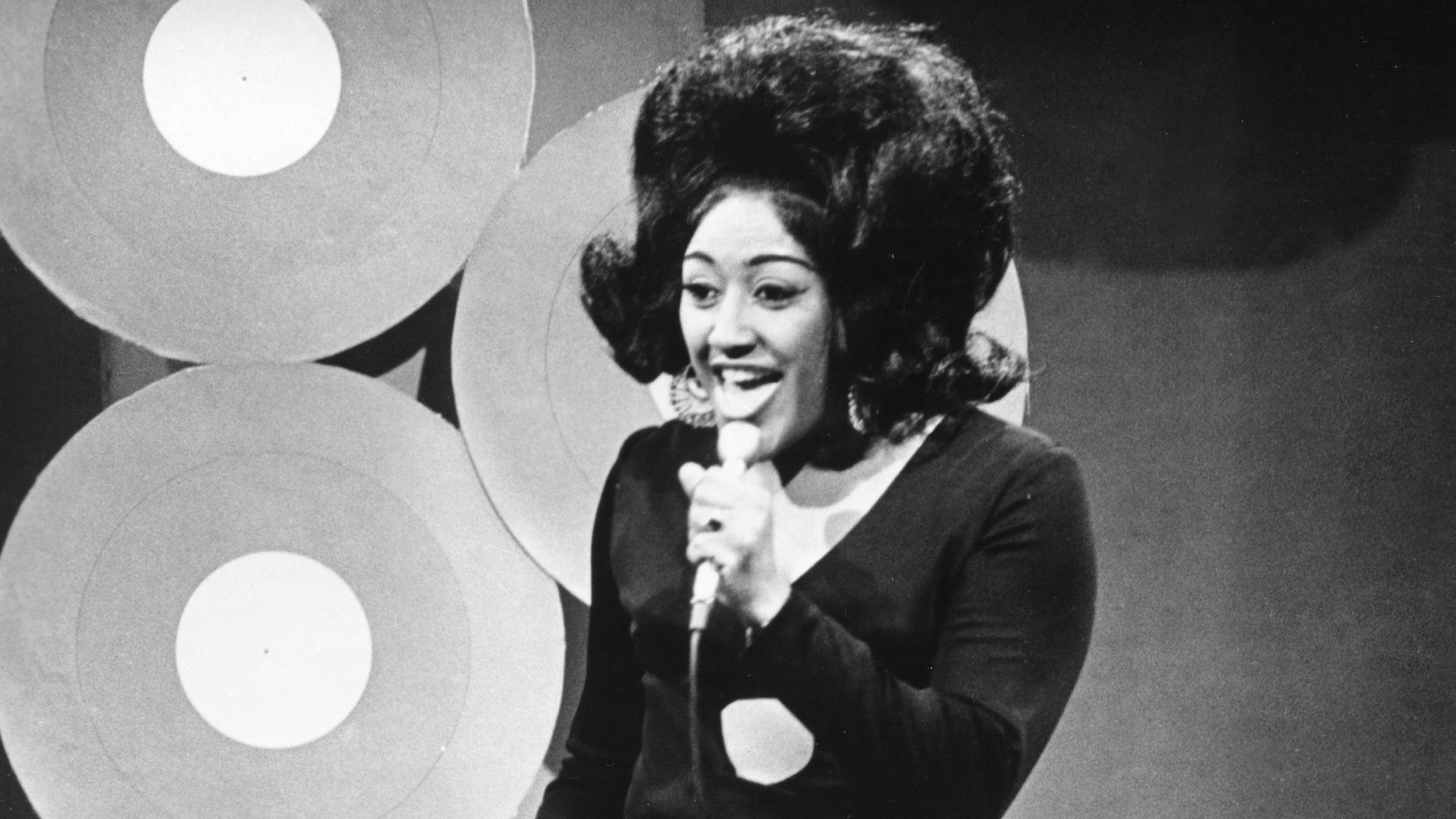 Image is a black and white photo of Jean Knight holding a microphone.