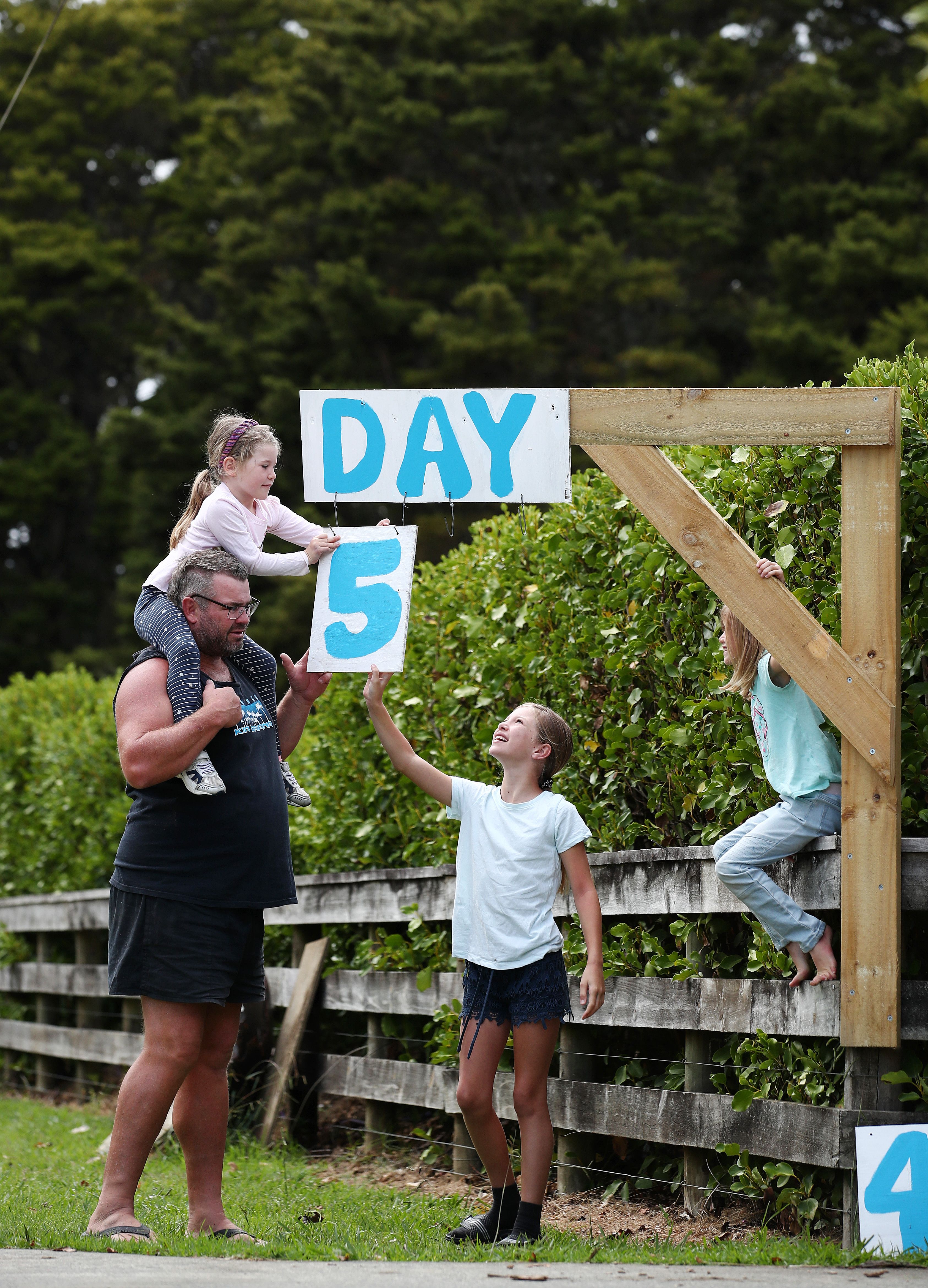 The Paddison family update their roadside isolation countdown sign in  in Auckland, New Zealand. 