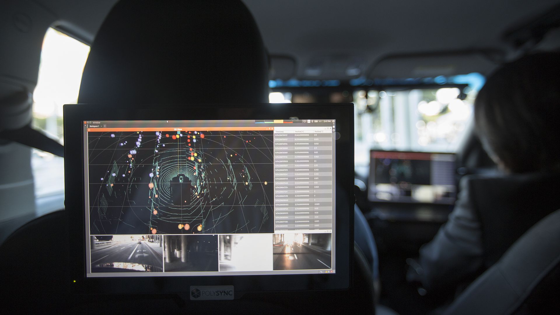 Photo of a backseat screen rendering a driverless car's surroundings 