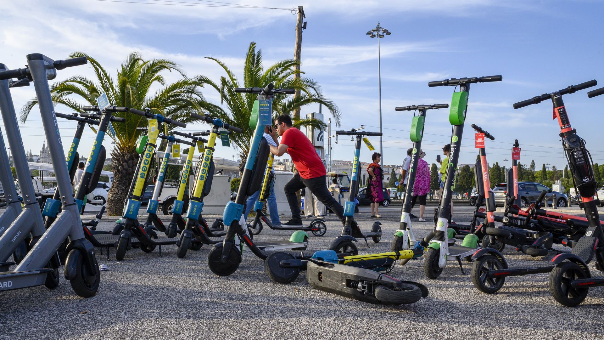 A man starts an e-scooter by a group of others left on an esplanade in Lisbon, Portugal.