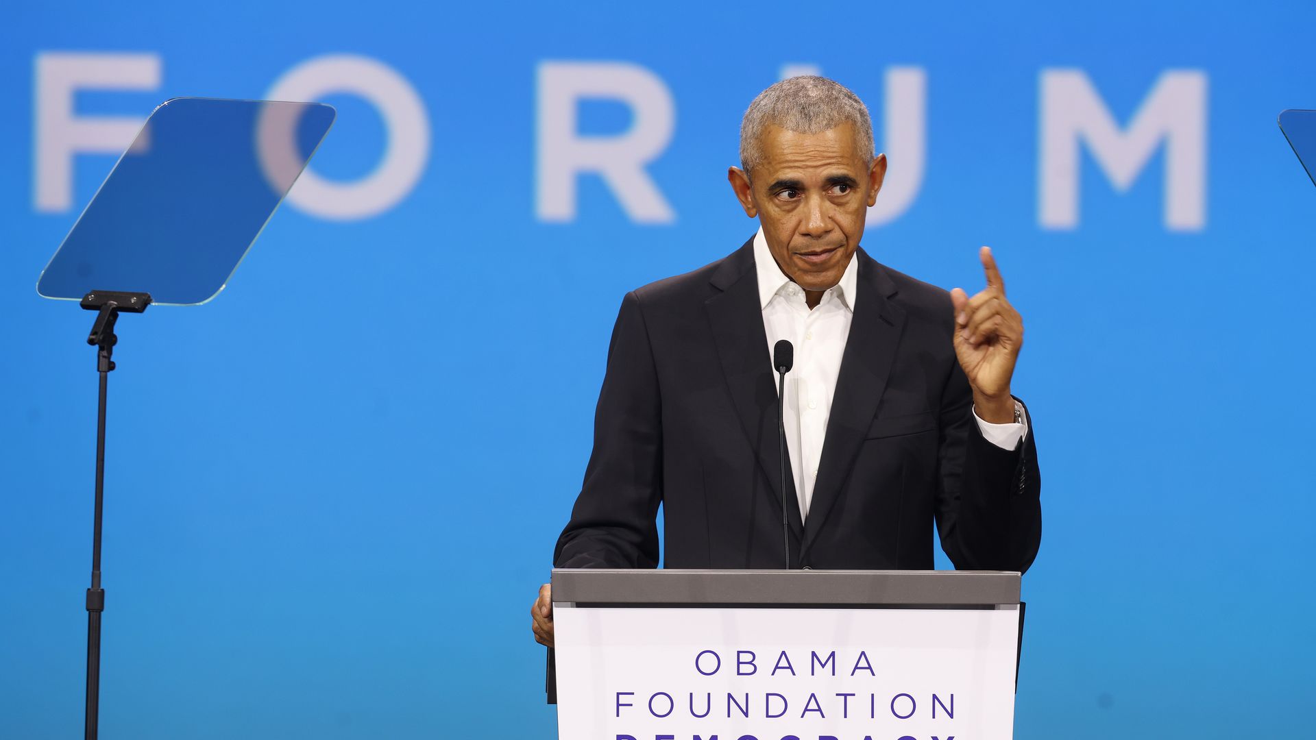 Obama speaks at a lectern in front of a blue background 