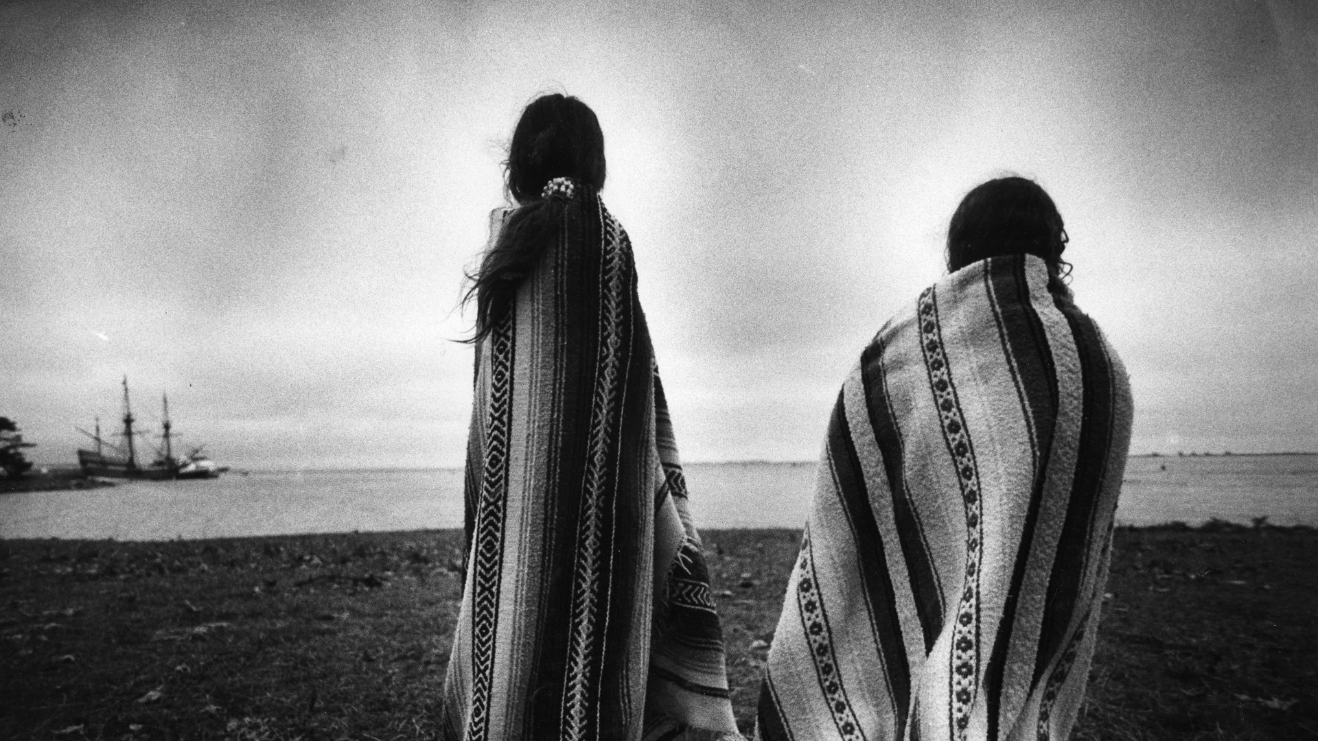 Weetoomoo Carey, 8, left, and her sister Jackolynn Carey, 5, Wampanoag Nipmucs from Mashpee, looked across to the Mayflower replica anchored near Plymouth Rock, where Native Americans gathered for a day of mourning in counterpoint to the Pilgrims' Thanksgiving. 