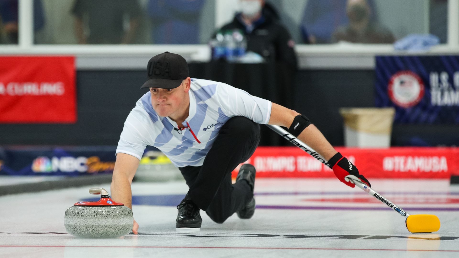 A man slides a curling stone across ice.