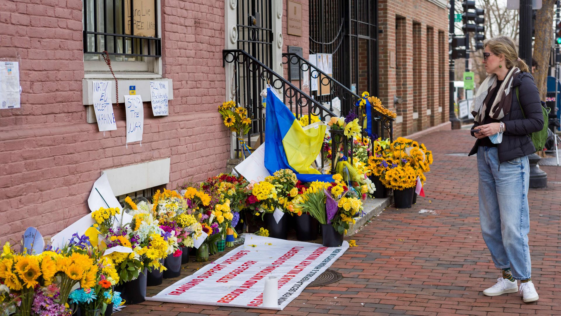 A woman is seen looking at flowers and other mementos left outside the Ukrainian embassy in Washington.