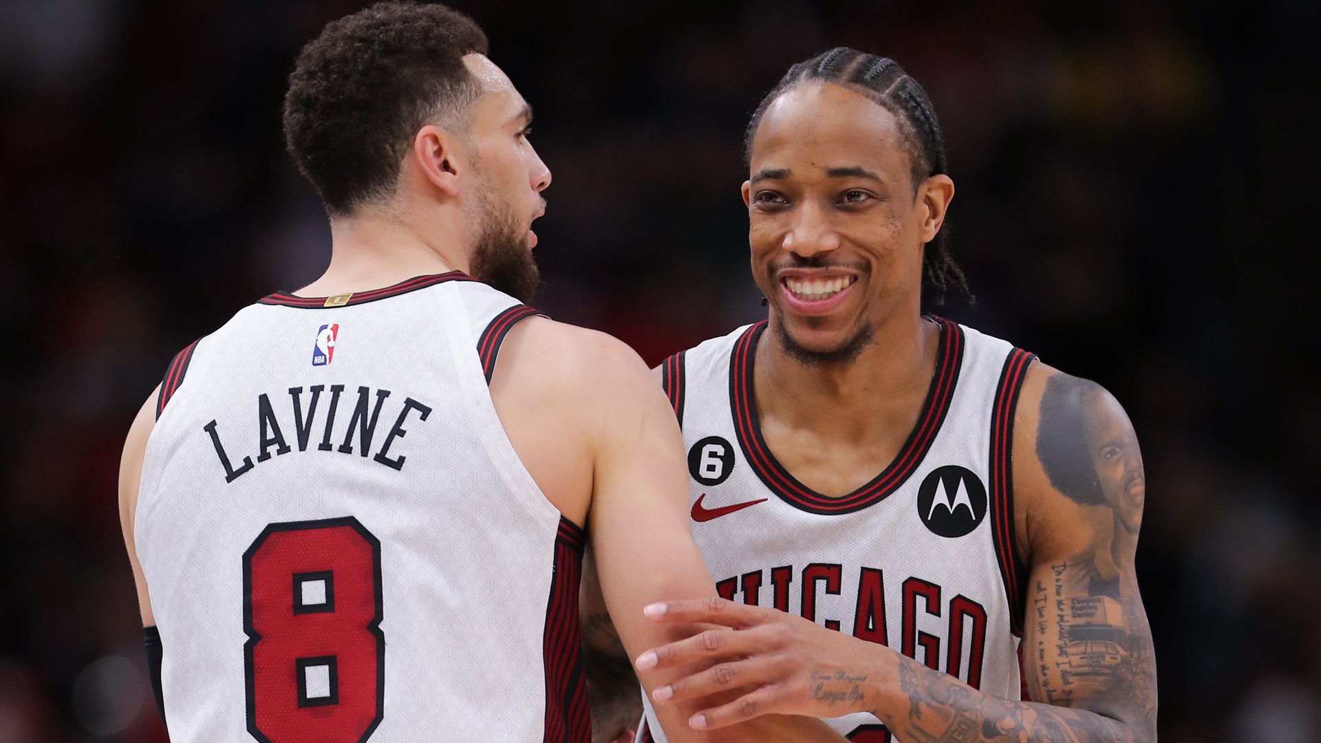 Photo of two basketball players smiling on court 