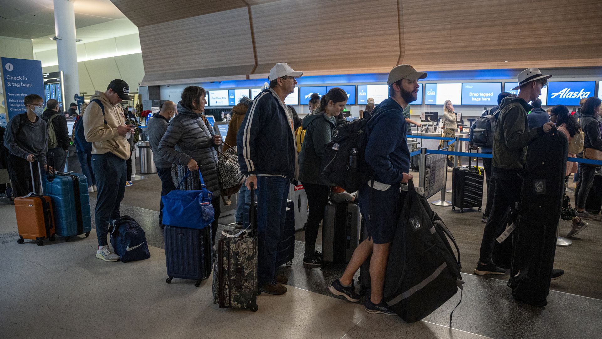 Travelers wait to check-in at the Alaska Airlines counter at San Francisco International Airport (SFO) in San Francisco, California, US, on Tuesday, Dec. 27, 2022