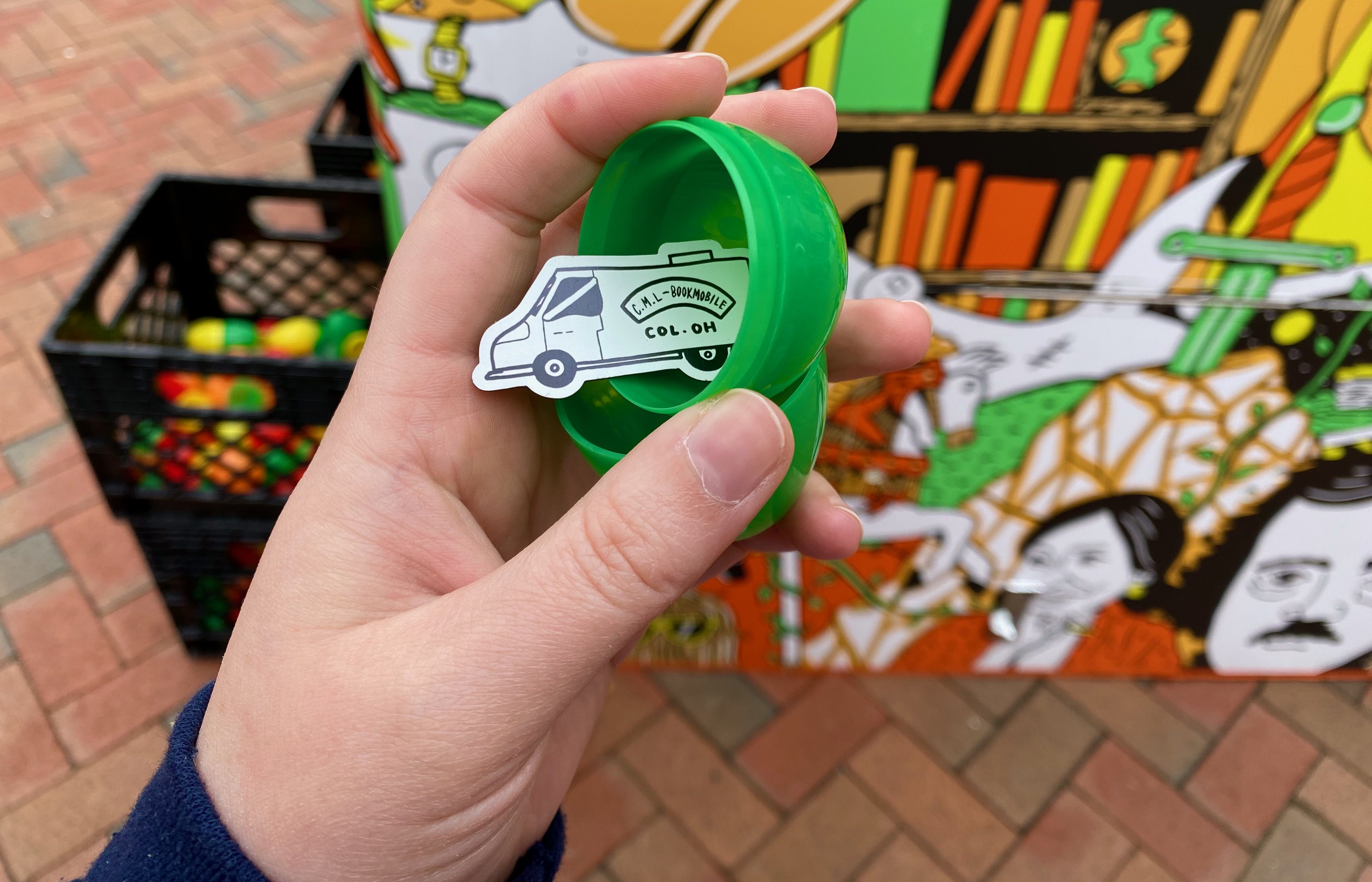 A green plastic egg with a magnet shaped like a white Bookmobile inside