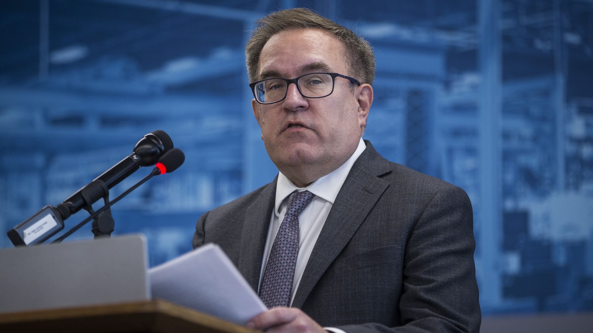 In this picture, EPA administrator Andrew Wheeler stands in a suit and tie and holds papers
