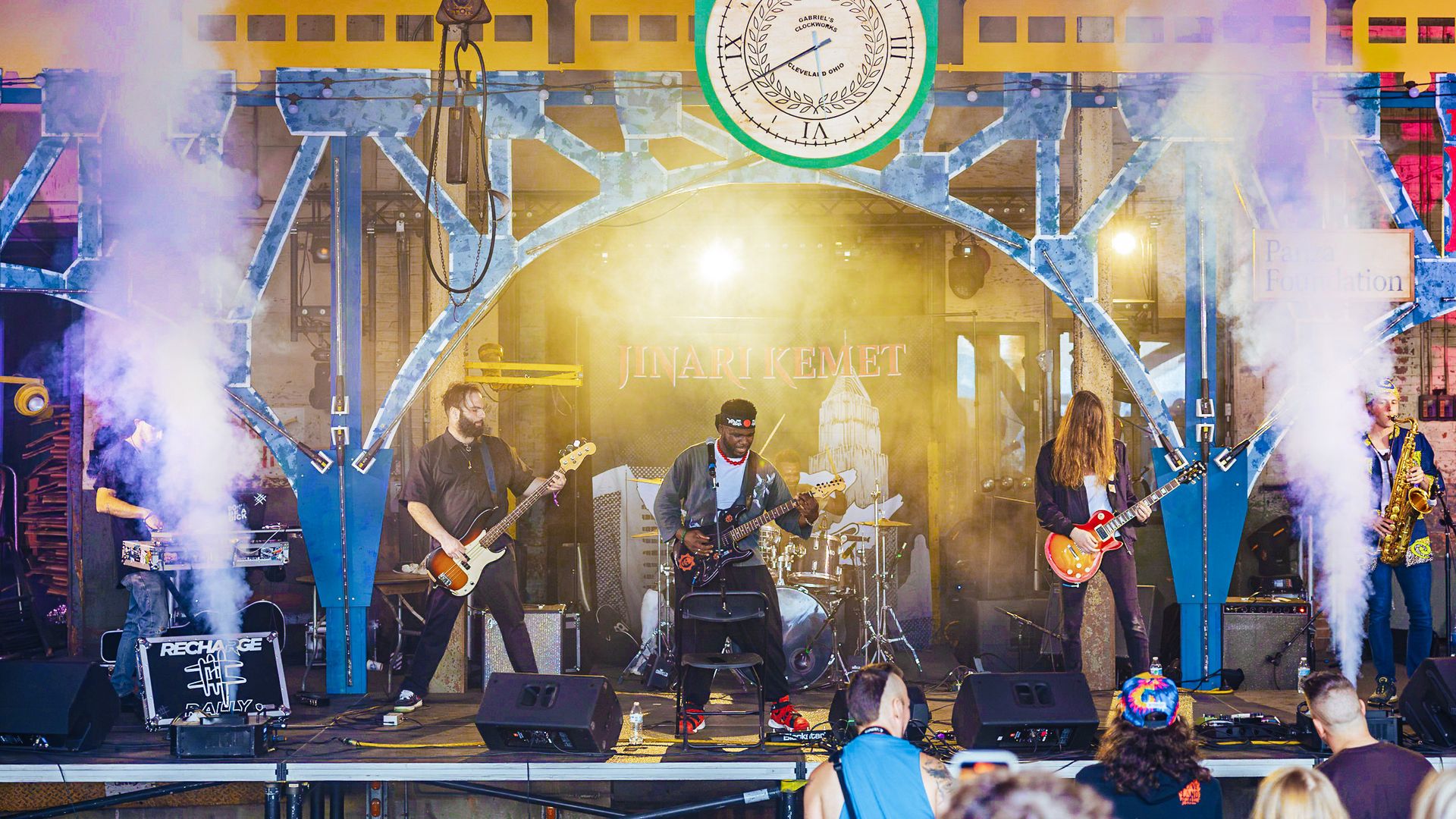 Photo of band playing on stage with smoke on either side