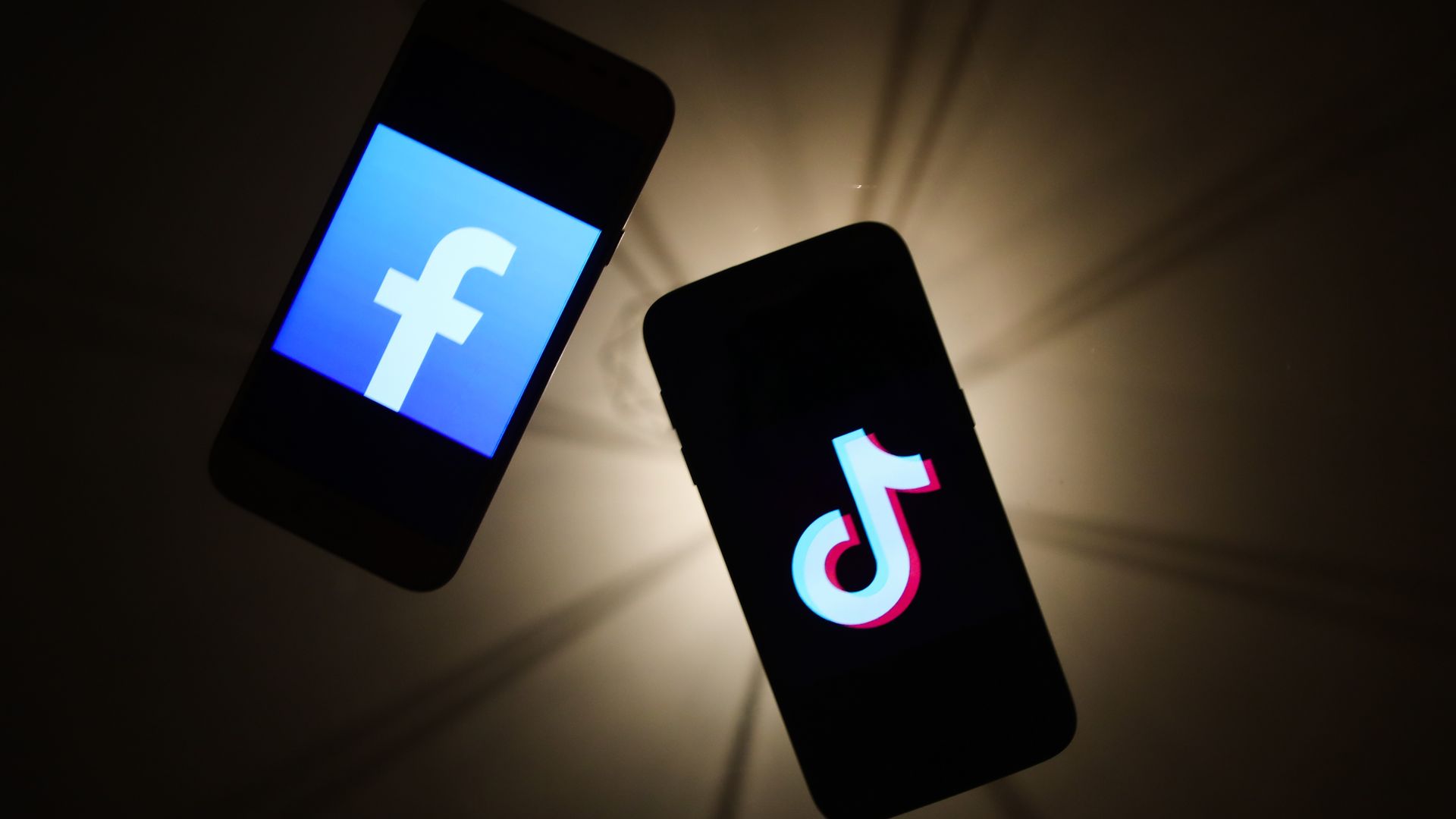 In this image, a phone screen with Facebook and another with TikTok are displayed