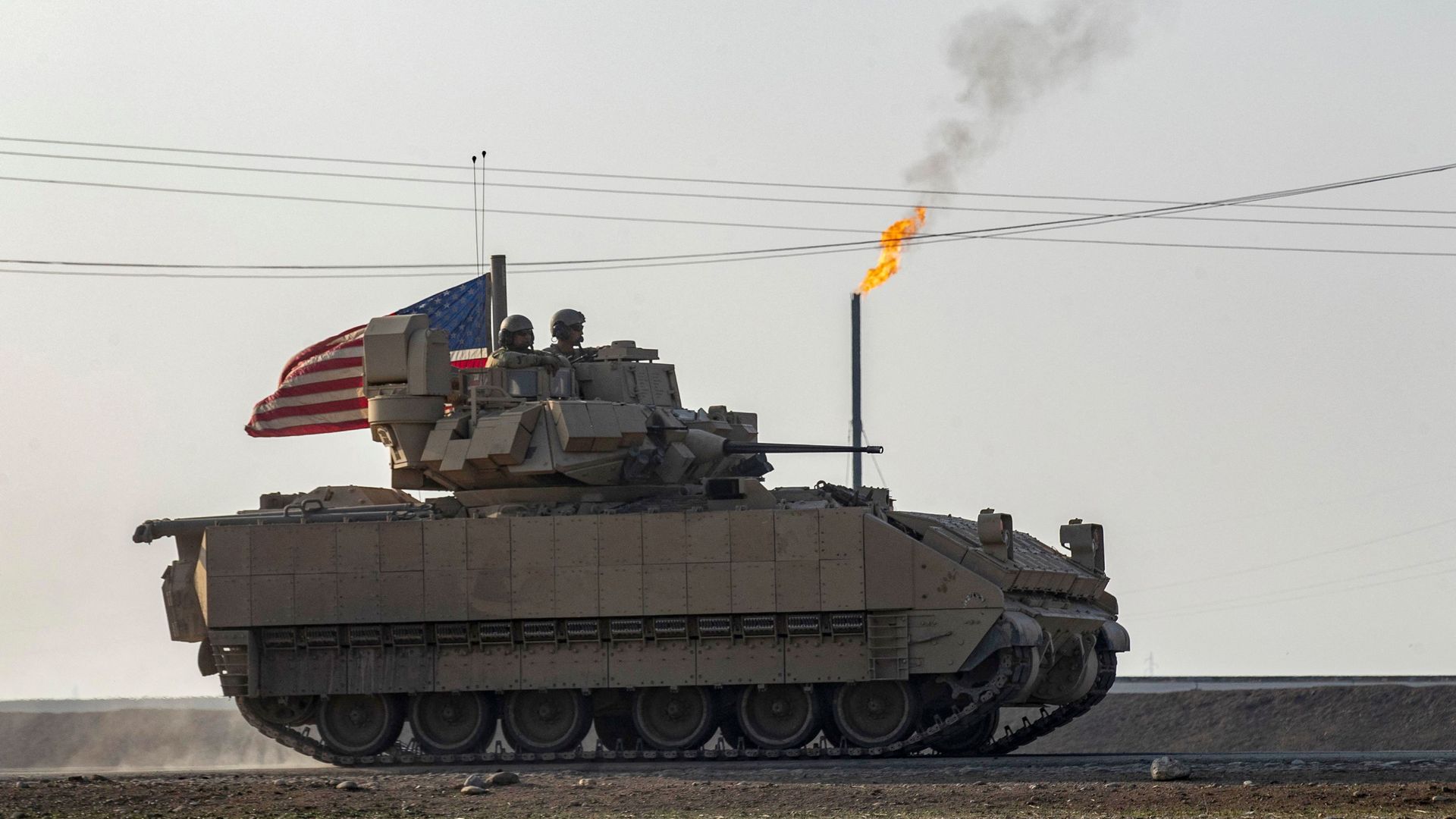US soldiers in a tank drive past a flare stack near a local oil field as they patrol the countryside of Rumaylan (Rmeilan) in Syria's northeastern Hasakeh province on December 4.