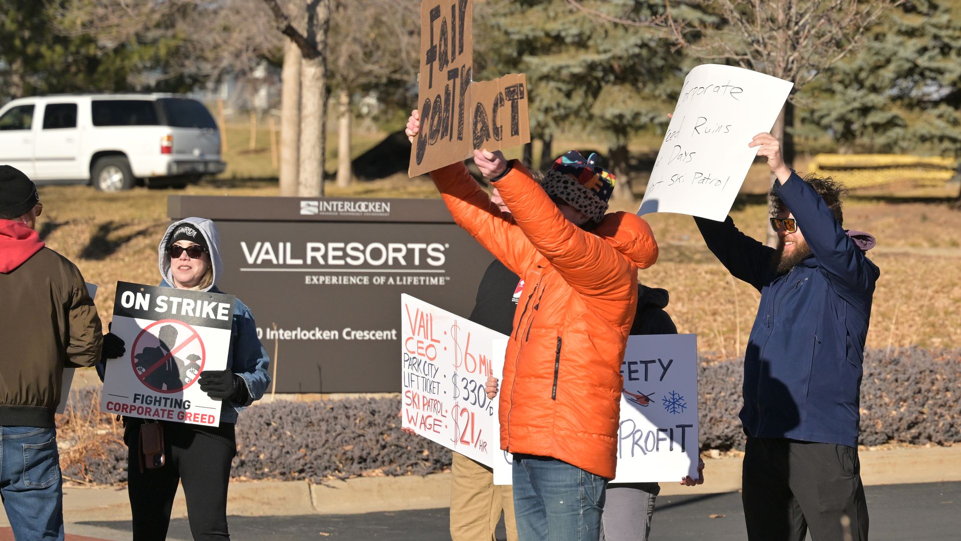 Picketers hold signs next to Vail Resorts headquarters.