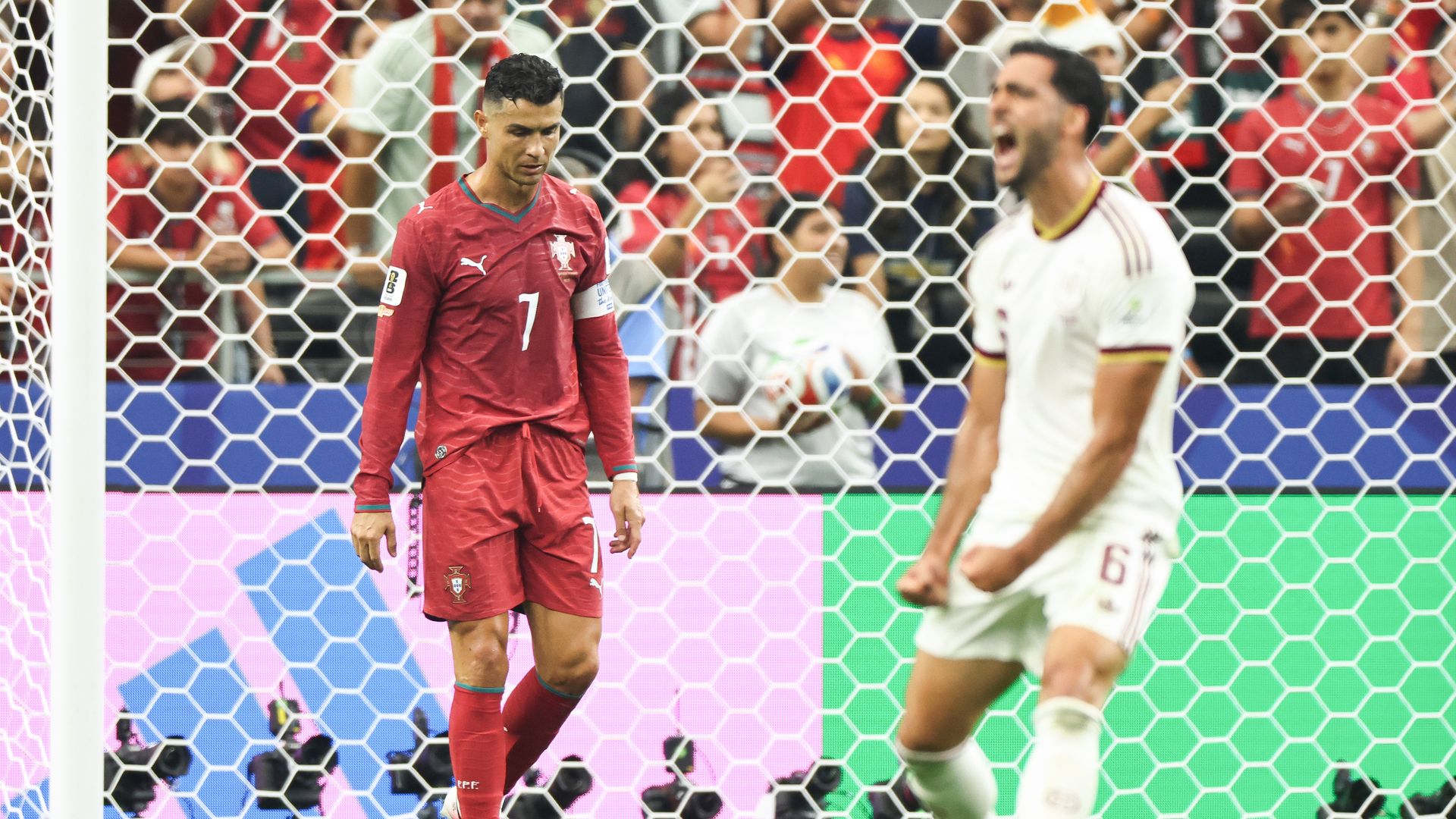 Cristiano Ronaldo looks down while a Spain player screams in celebration.
