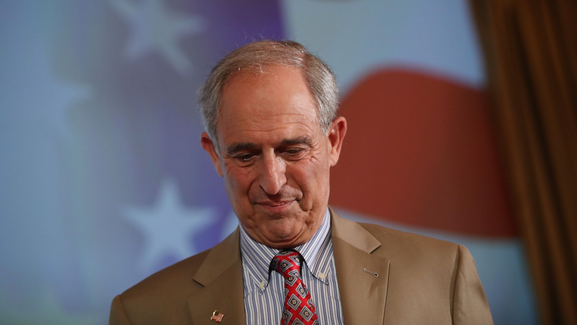 Lanny Davis looks down while on stage