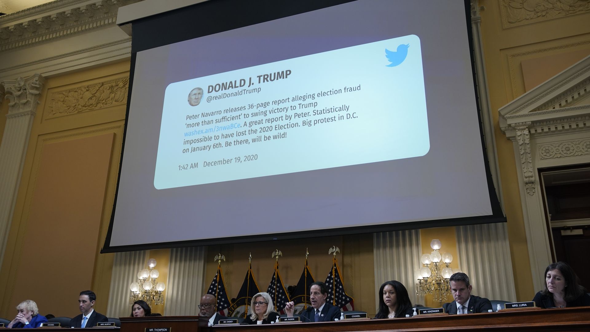A draft tweet from former U.S. President Donald Trump appears on a video screen above members of the Select Committee to Investigate the January 6th Attack.