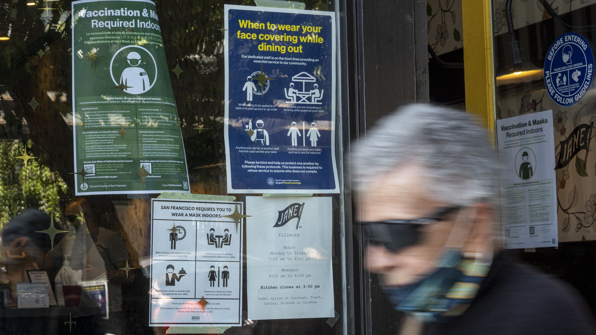 A person walking past COVID-19 signs. 