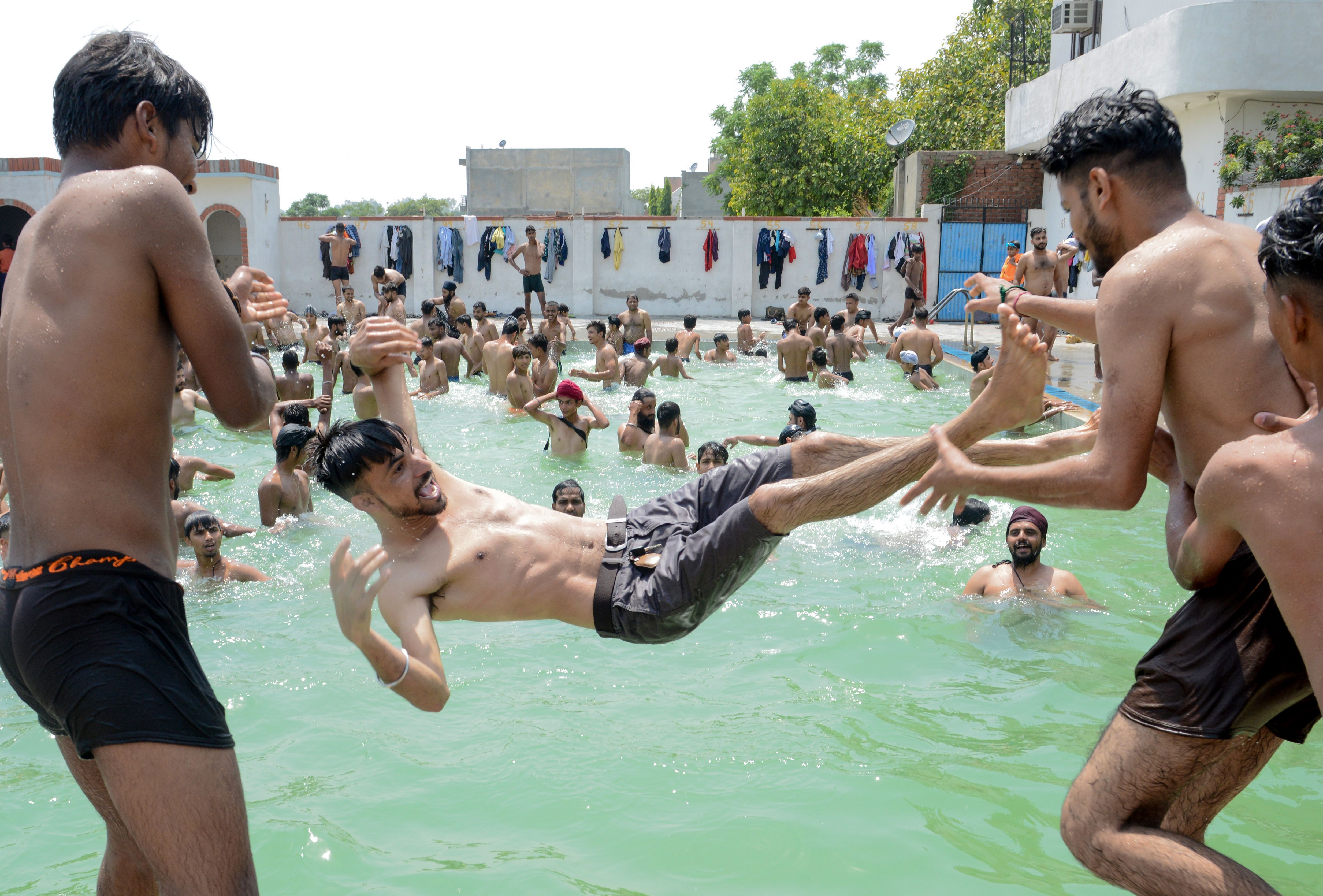 Youths play in a swimming pool on a hot summer day on the outskirts of Amritsar on June 2, 2019. 