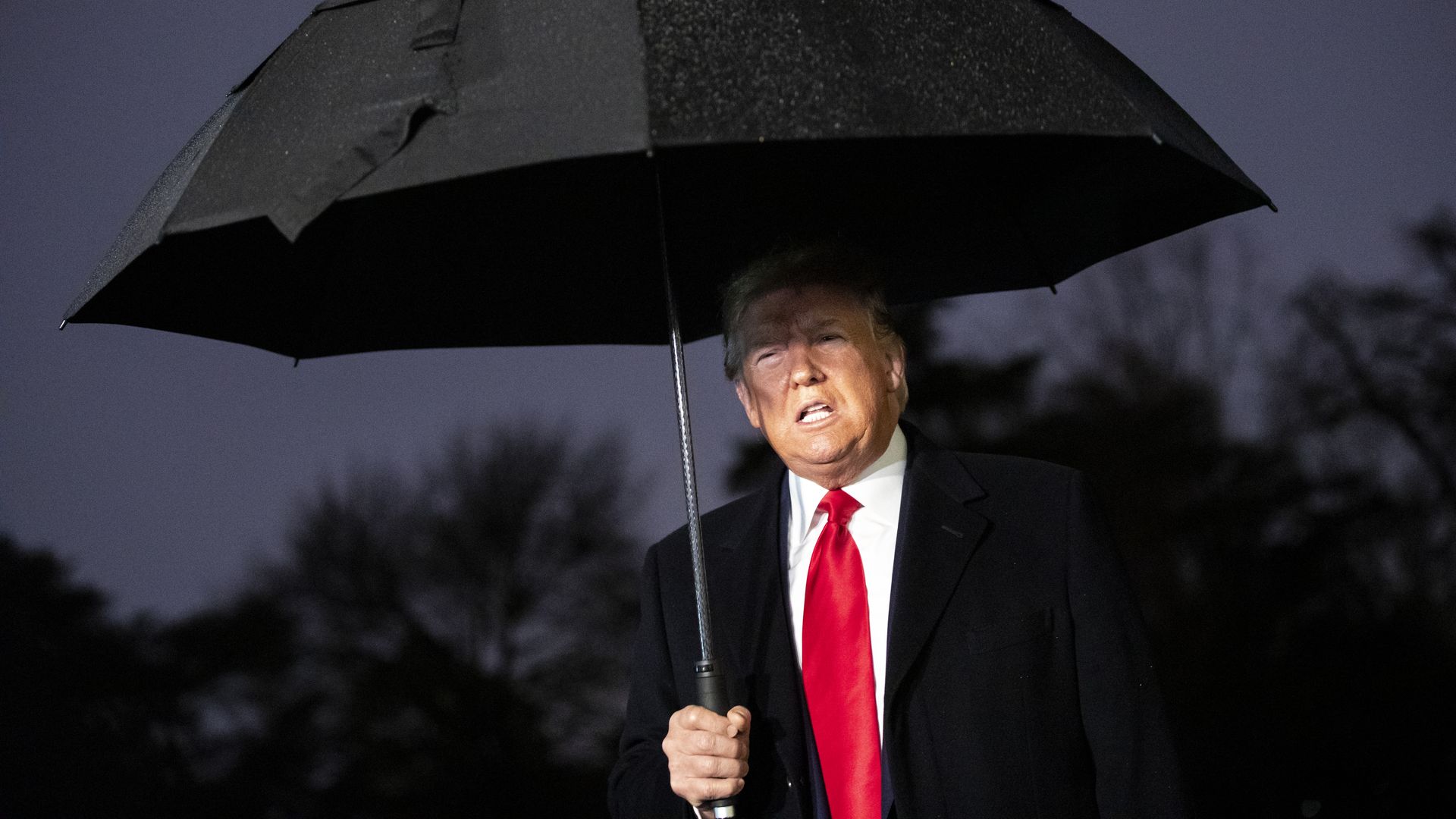 In this image, Trump holds an umbrella