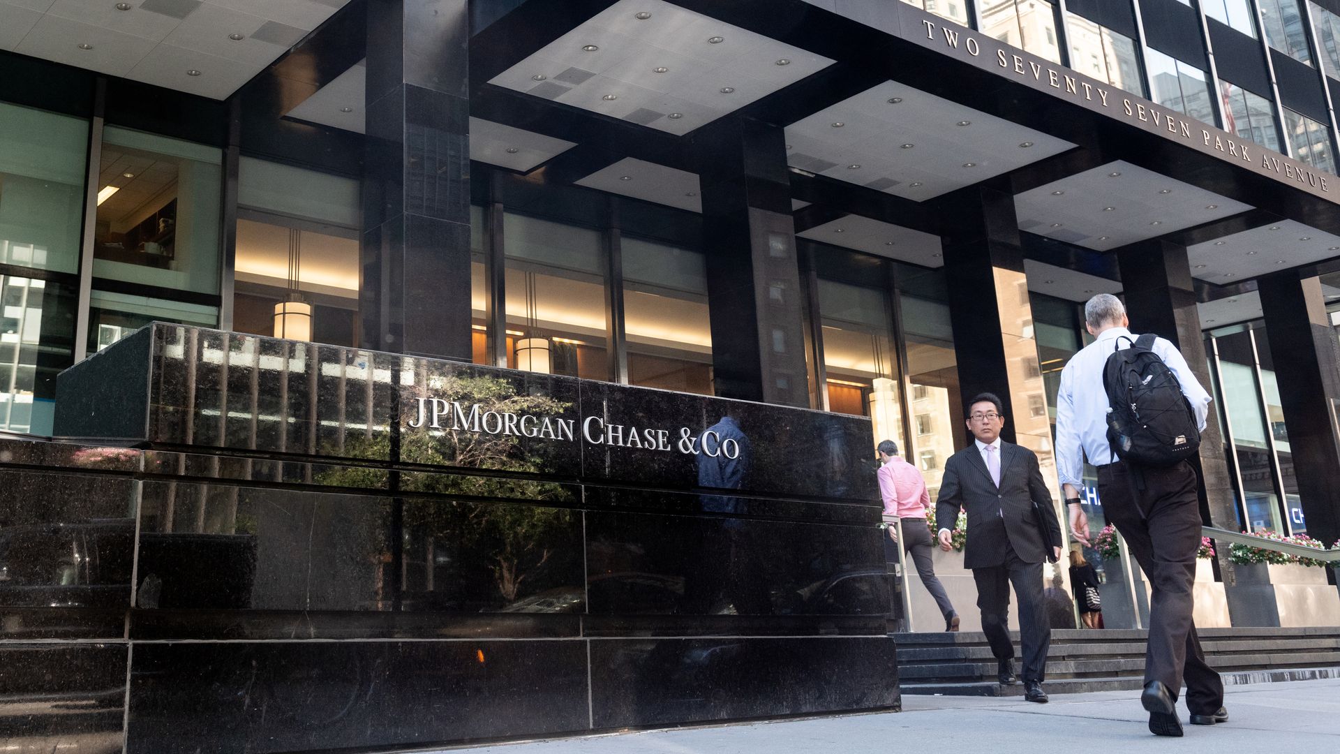 Two people walking outside JPMorgan Chase & Co. building on Park Avenue in New York City.