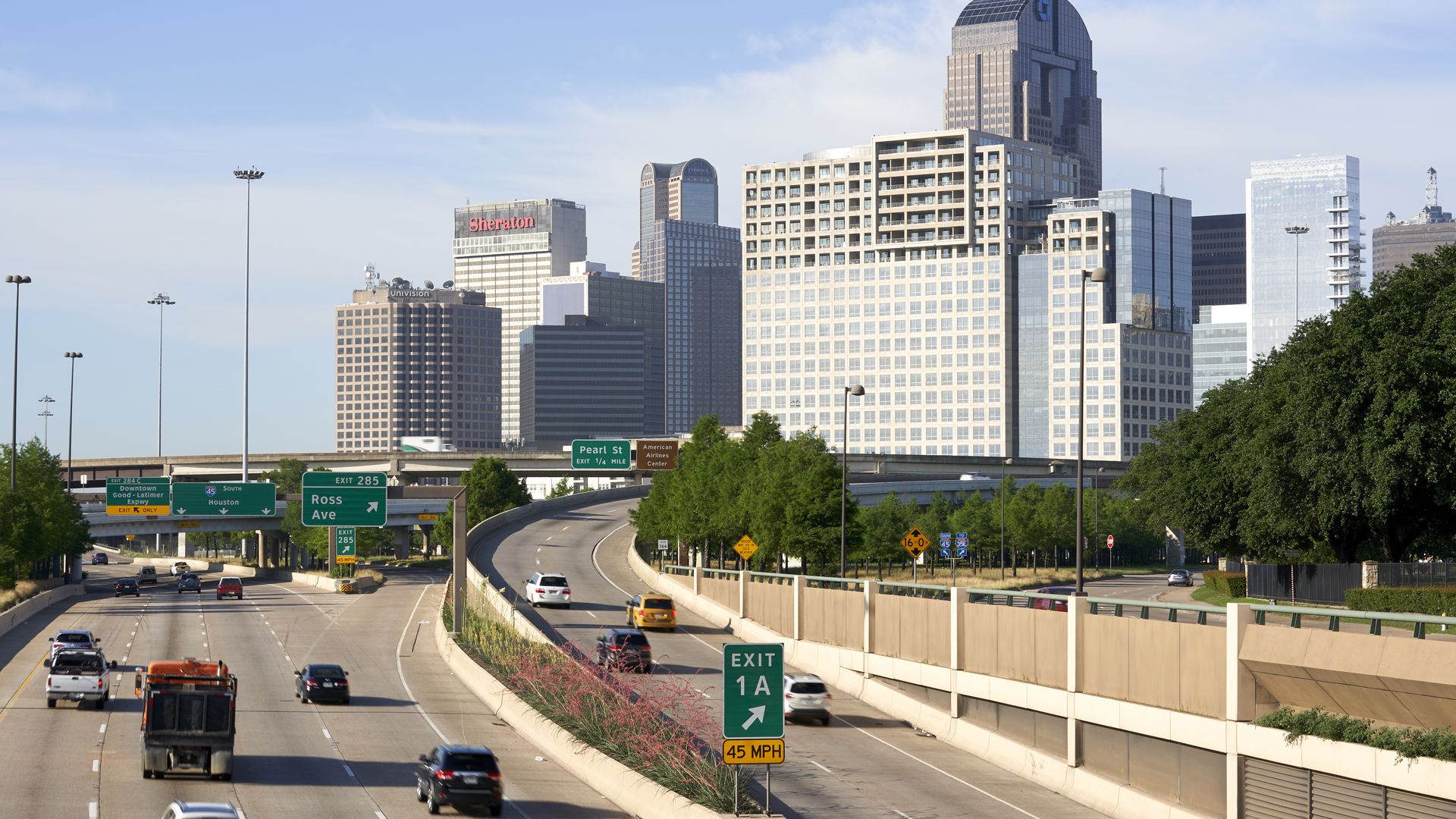 US 75 splits near downtown Dallas, with multiple green exit signs in the direction of tall city buildings. 
