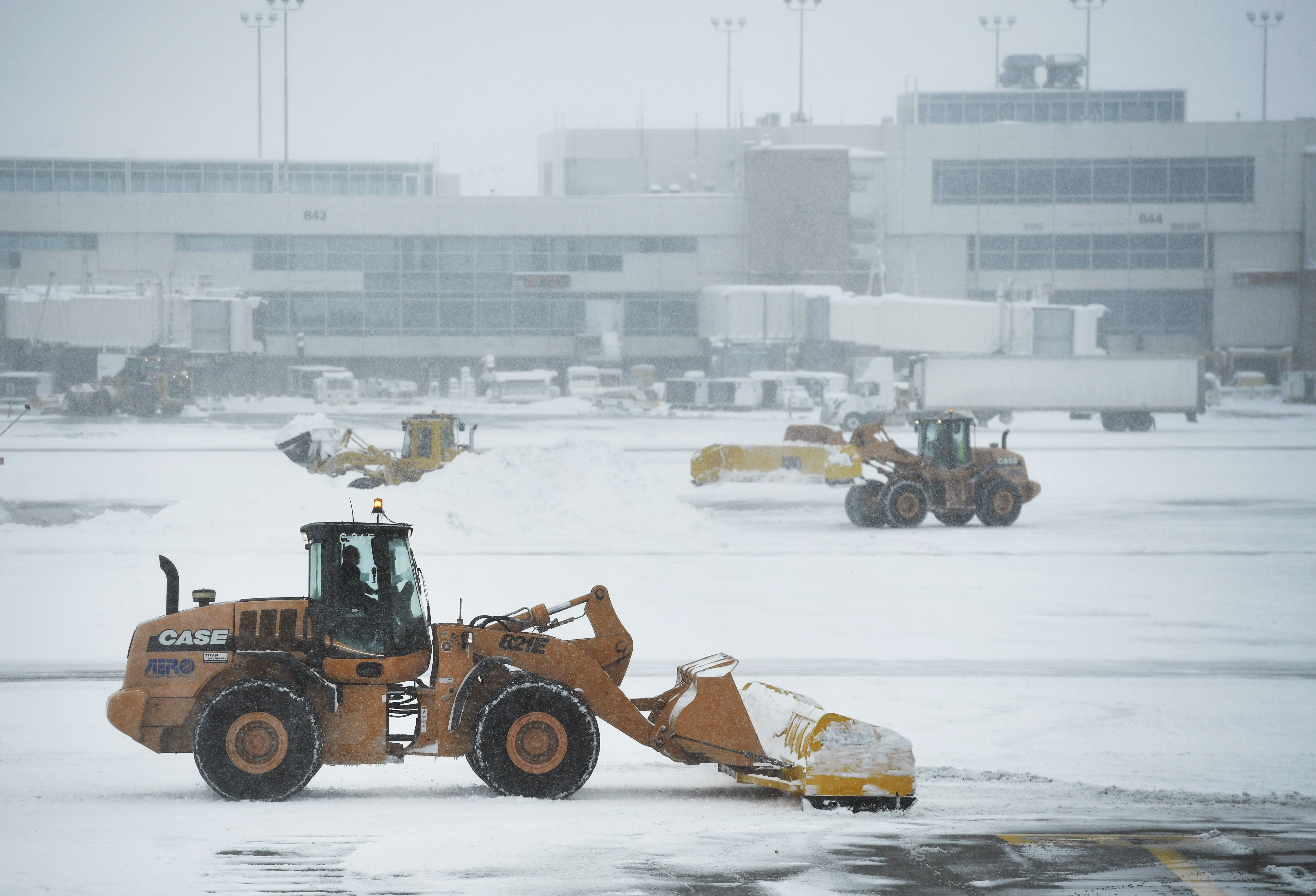 Crews work to clear heavy snow in-between concourses at Denver International Airport 
