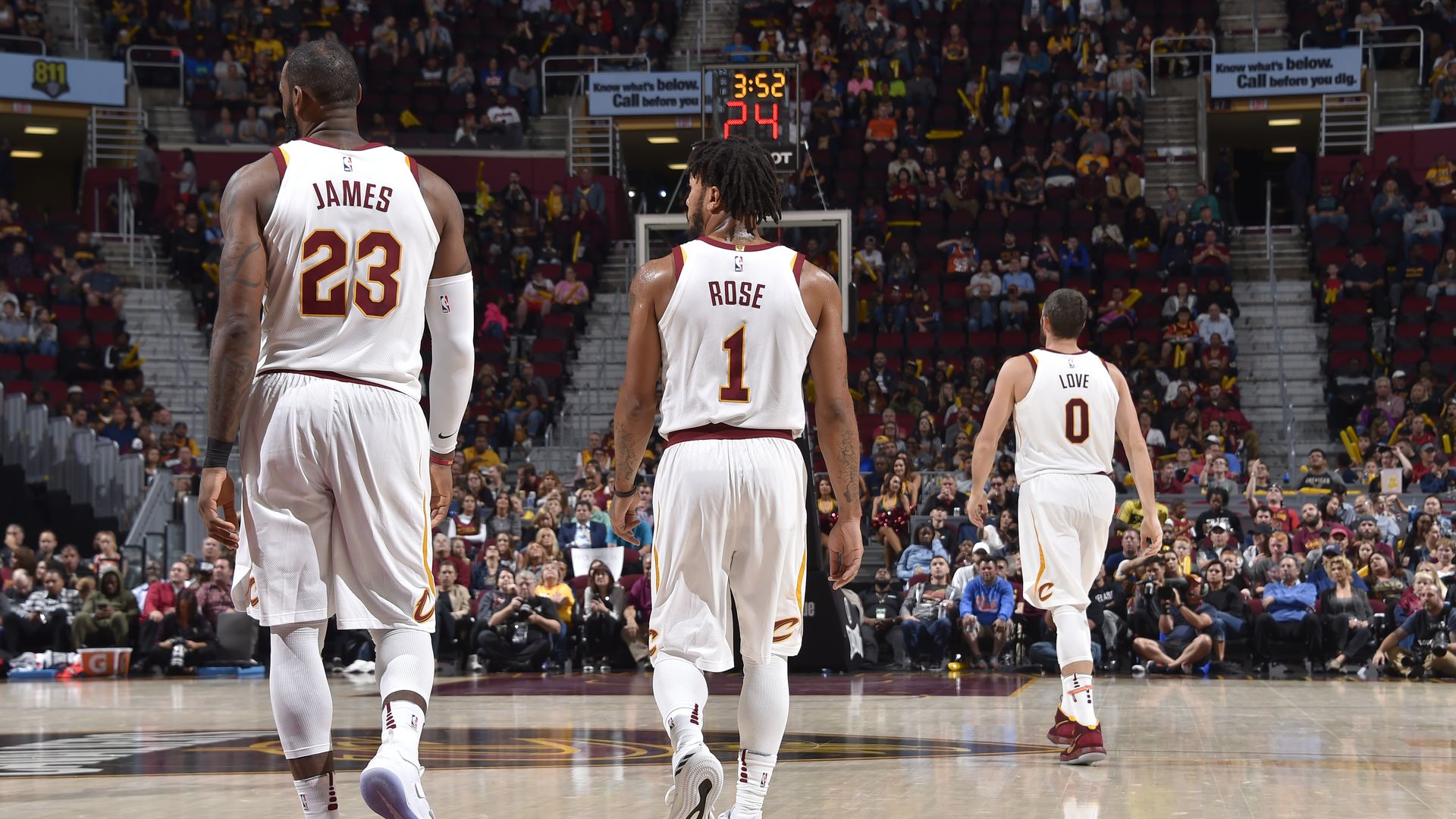 Photo of Derrick Rose in white Cavs uniform, from behind, between LeBron James and Kevin Love