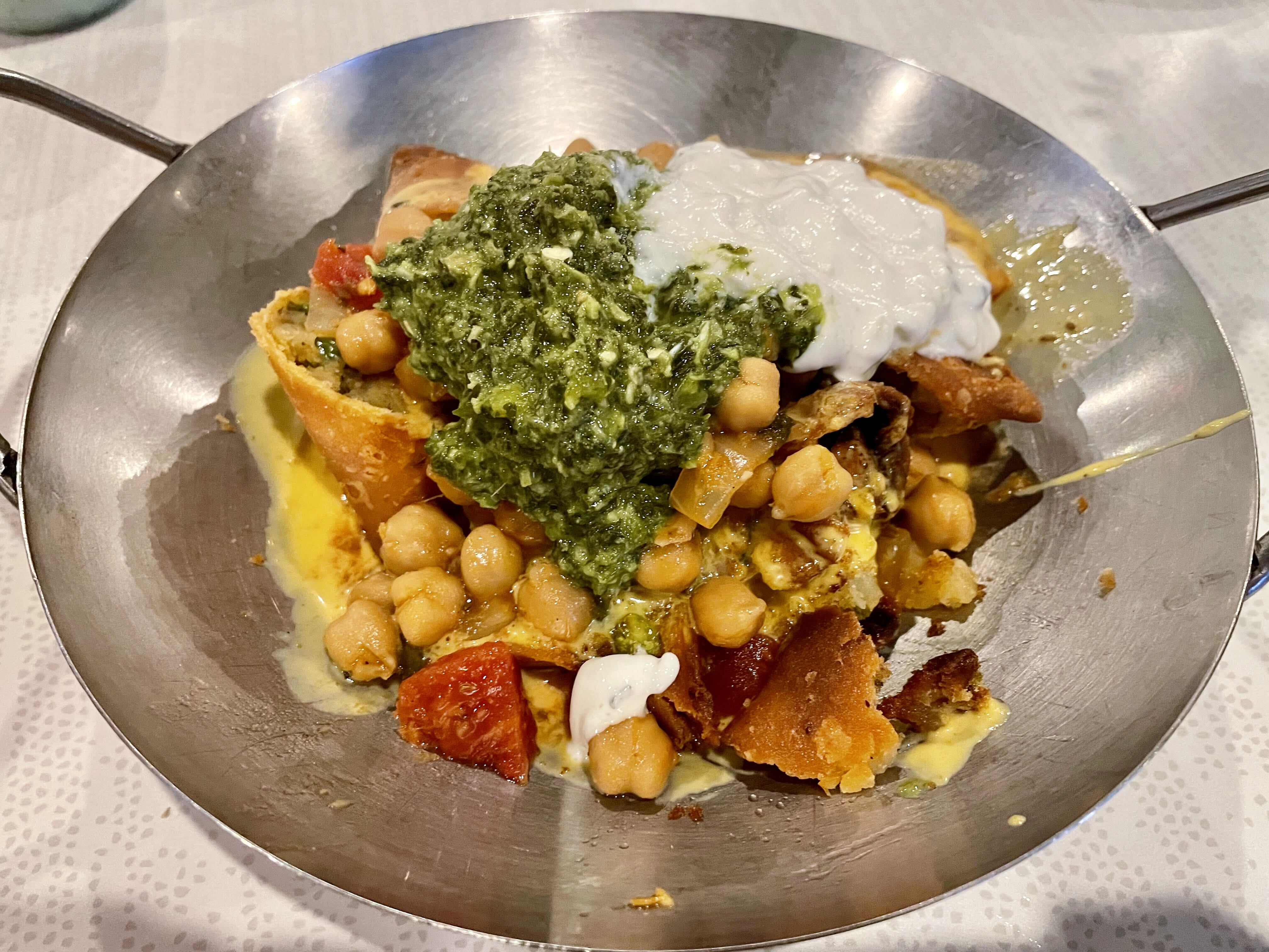 A silver bowl filled with an assortment of vegetables and sauces.