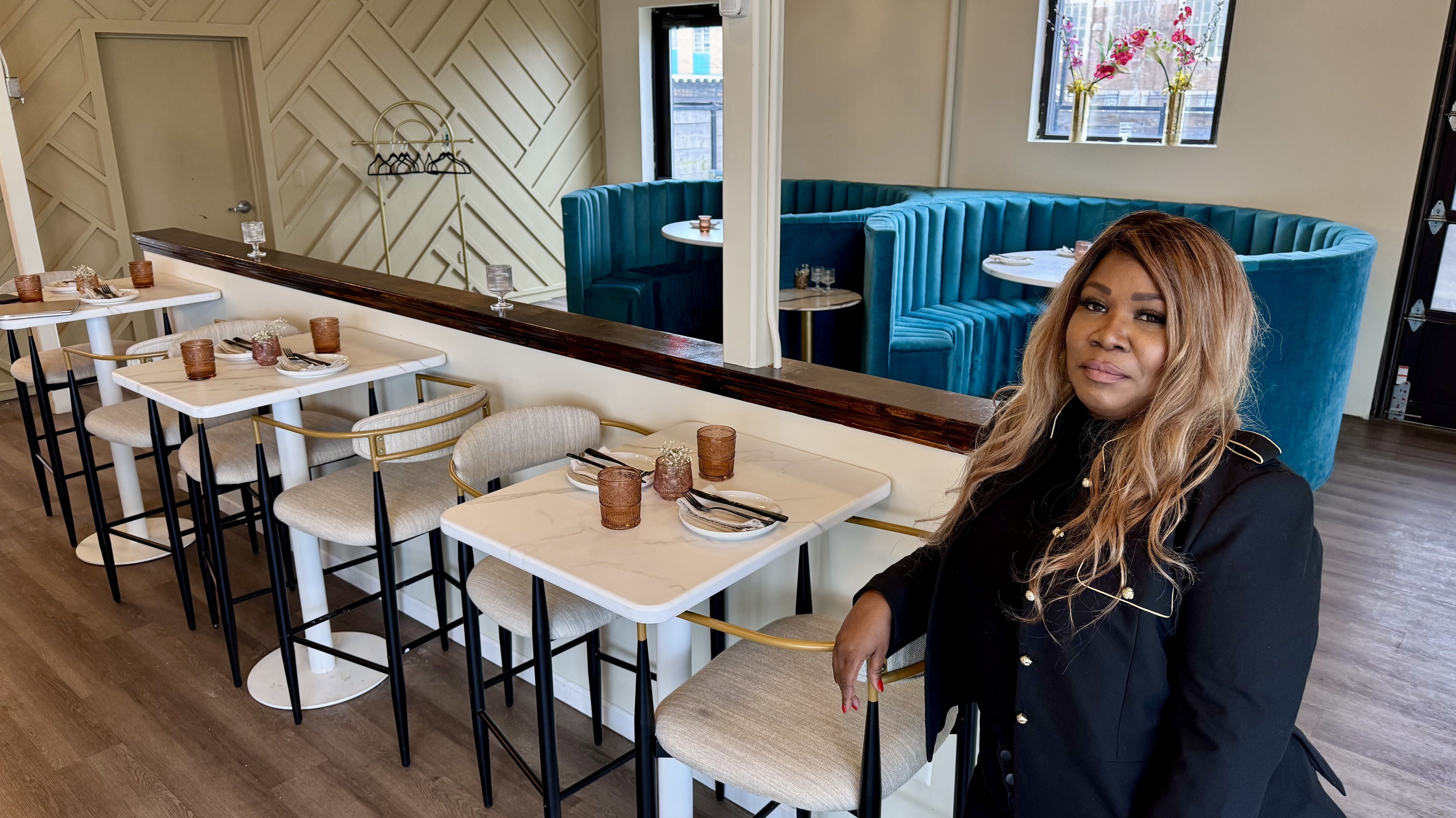 Nya Marshall poses in front of crisp white tables and velvety blue booths at Antidote. 