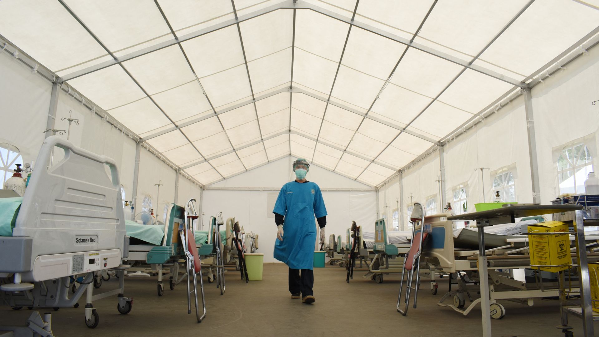 Photo of a person in a mask and scrubs walking in a medical area