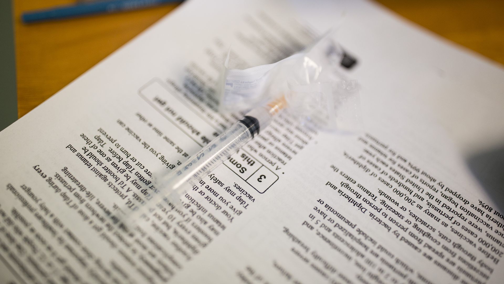 In this image, a syringe is place don top of a sheet of paper.