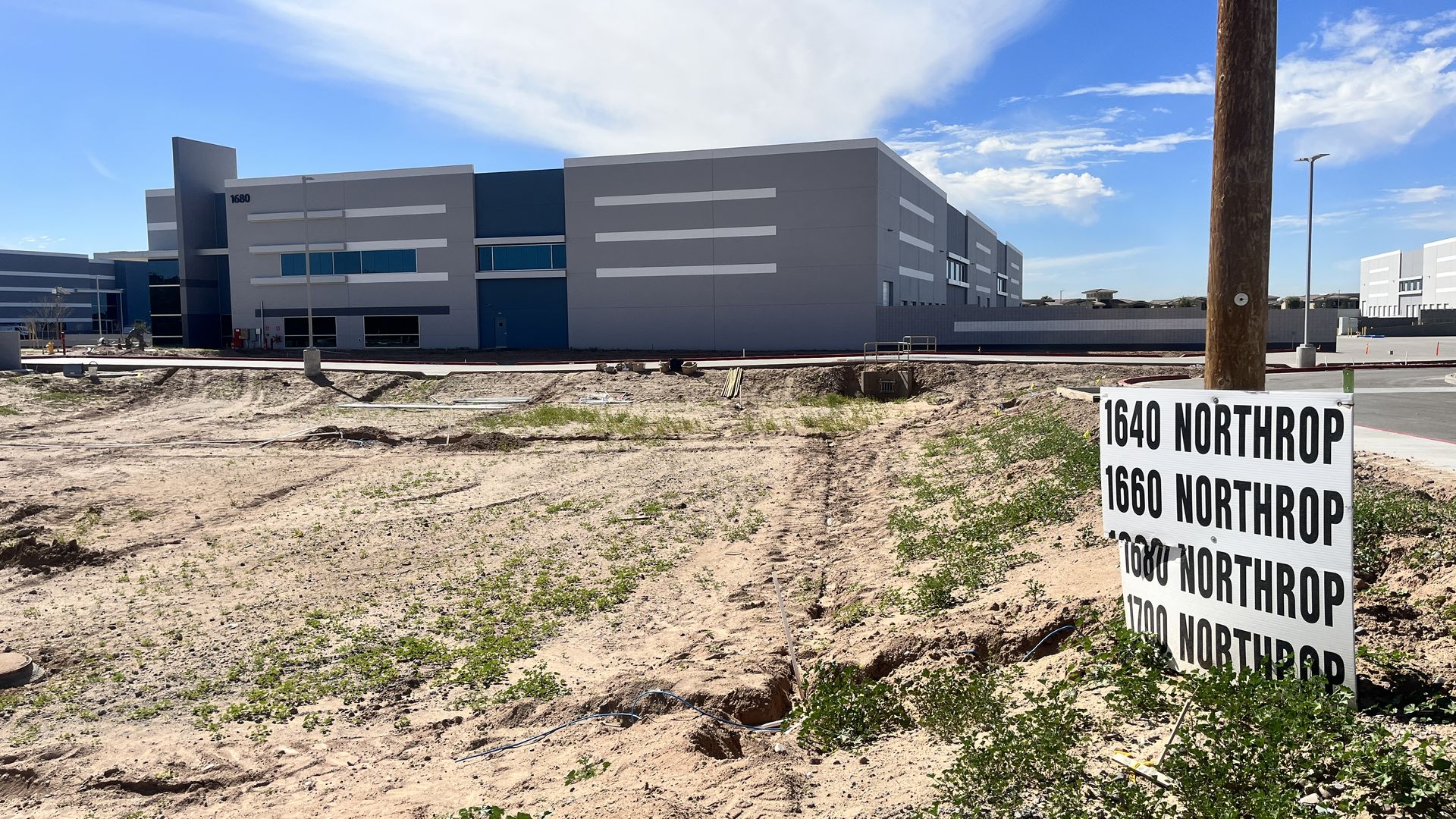 A new warehouse with a sign in the foreground with addresses.