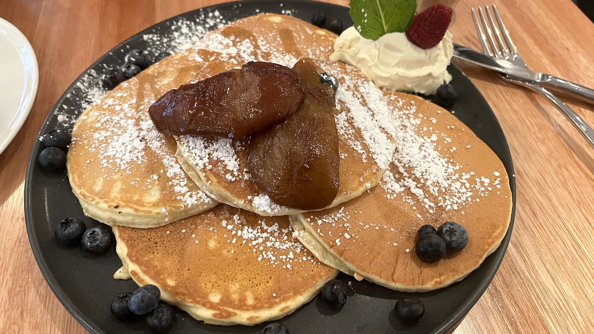 Three pancakes with poached pears and blueberries on top.