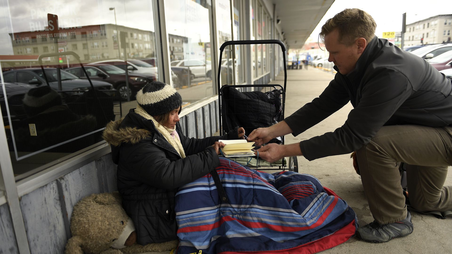 A photo of a social worker helping a homeless woman on the sidewalk